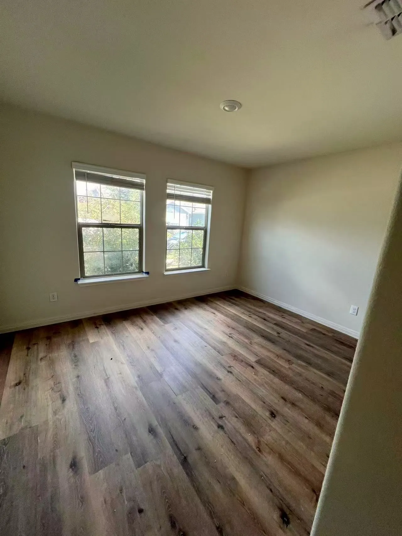Wood-finish flooring, recessed ceiling lighting, and two windows with blinds