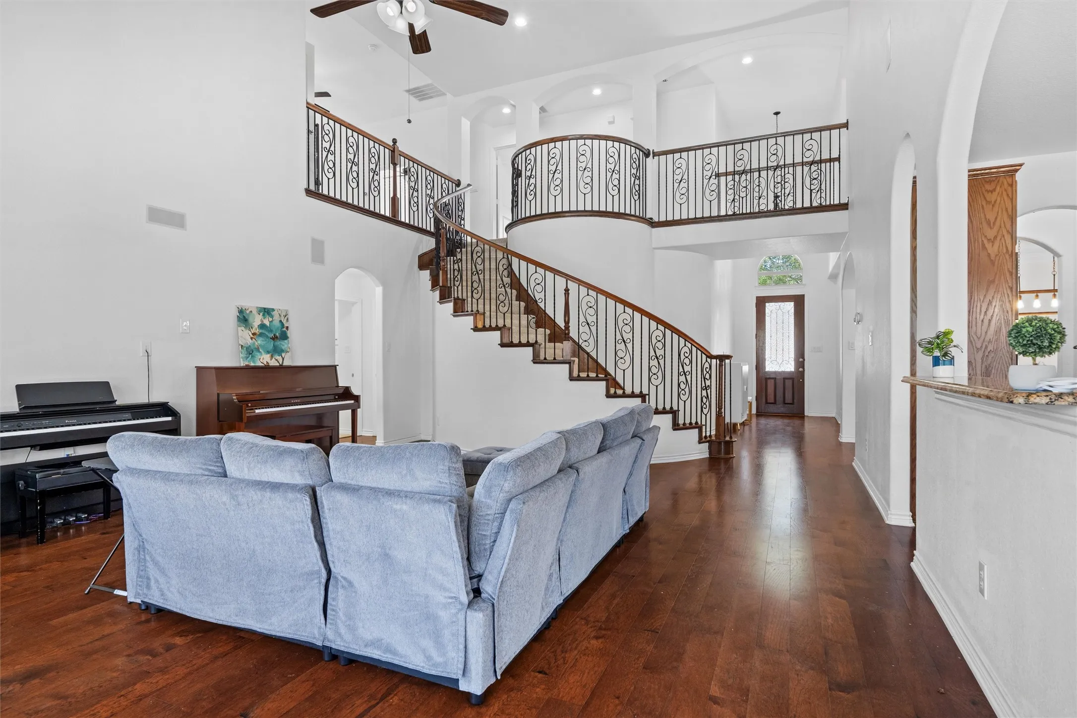 Two-story foyer with a curved staircase, wrought iron balusters, and wood-finish flooring