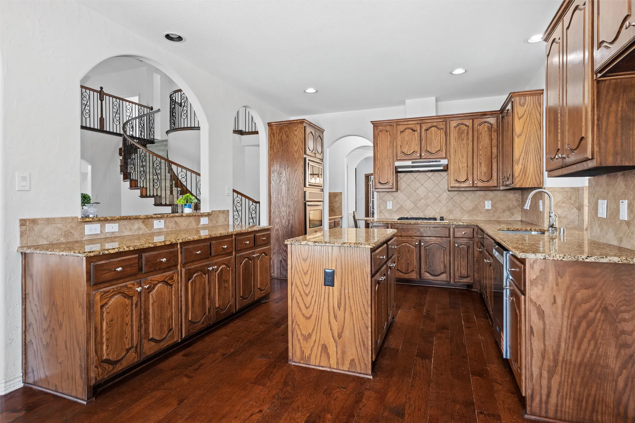 Elegant kitchen featuring rich wood cabinetry with detailed panel doors, granite countertops, stainless steel appliances, and a large center island with seating
