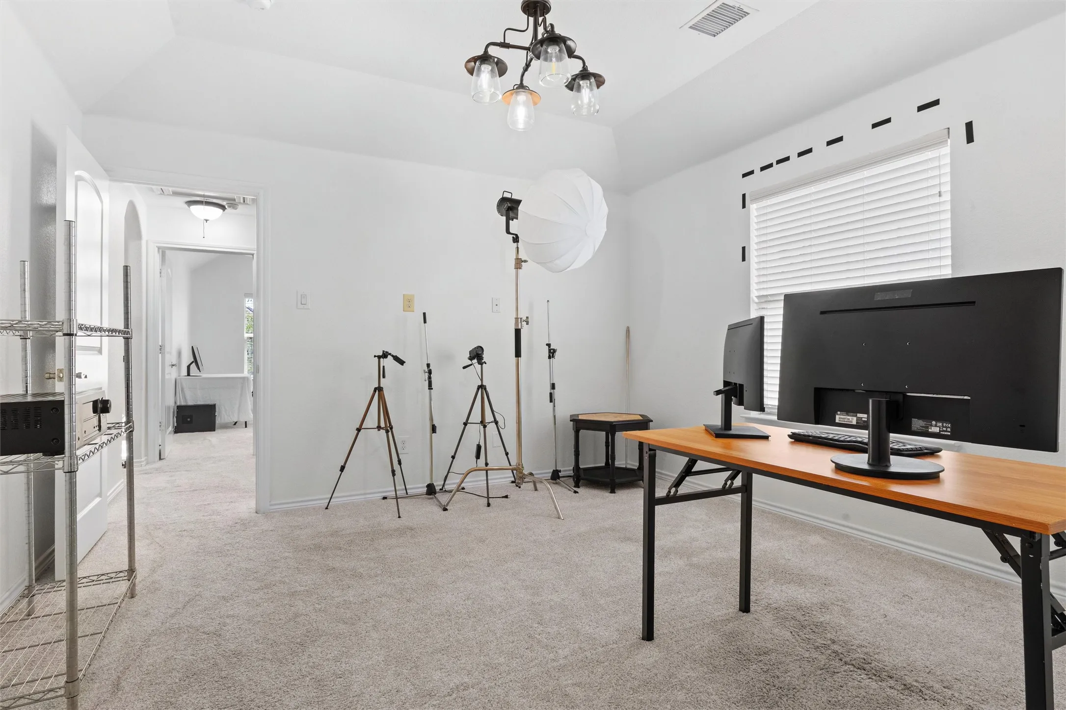 Carpeted room featuring a ceiling light fixture, window with blinds, and white walls