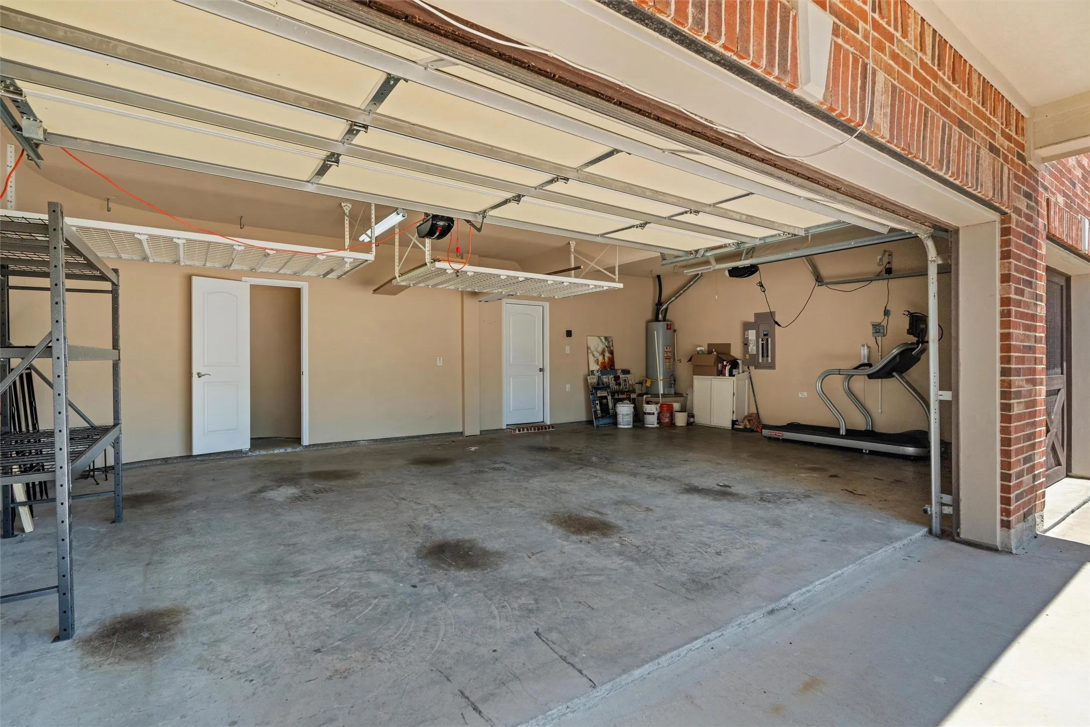 Spacious garage featuring a concrete floor, two white panel doors, and overhead storage racks