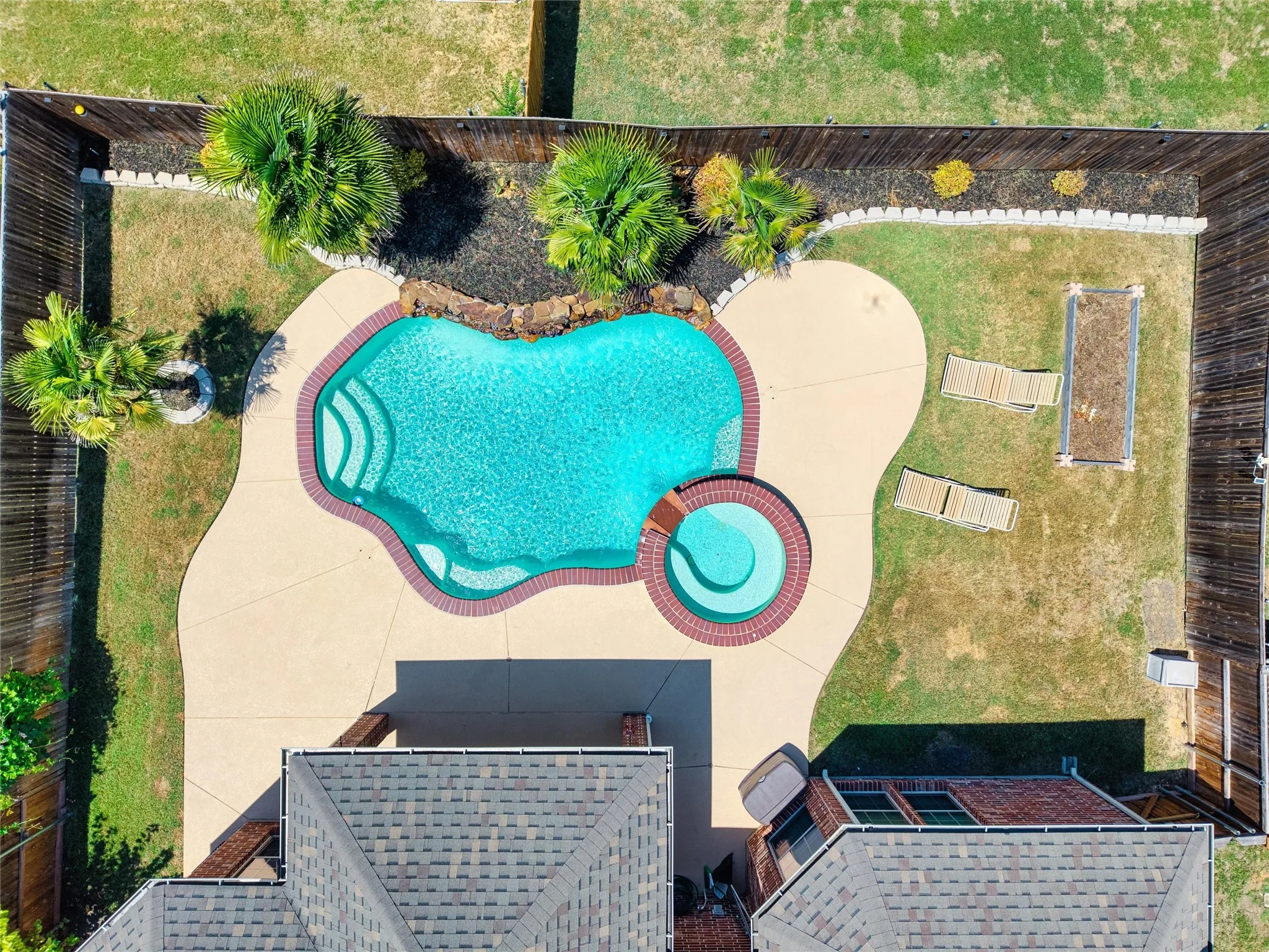 Private backyard featuring a freeform swimming pool, integrated spa, and concrete patio