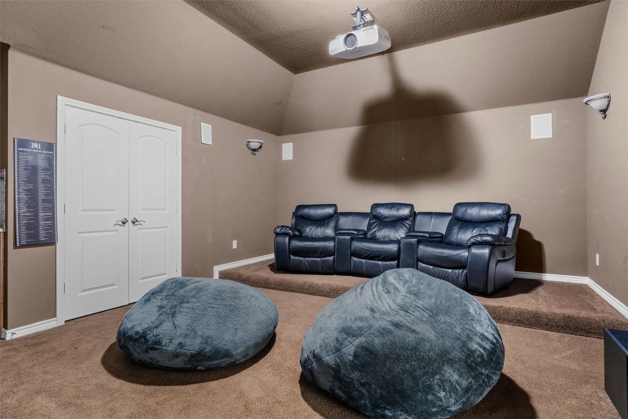 Integrated ceiling projector, vaulted ceiling, built-in wall speakers, wall sconce lighting, and a raised platform