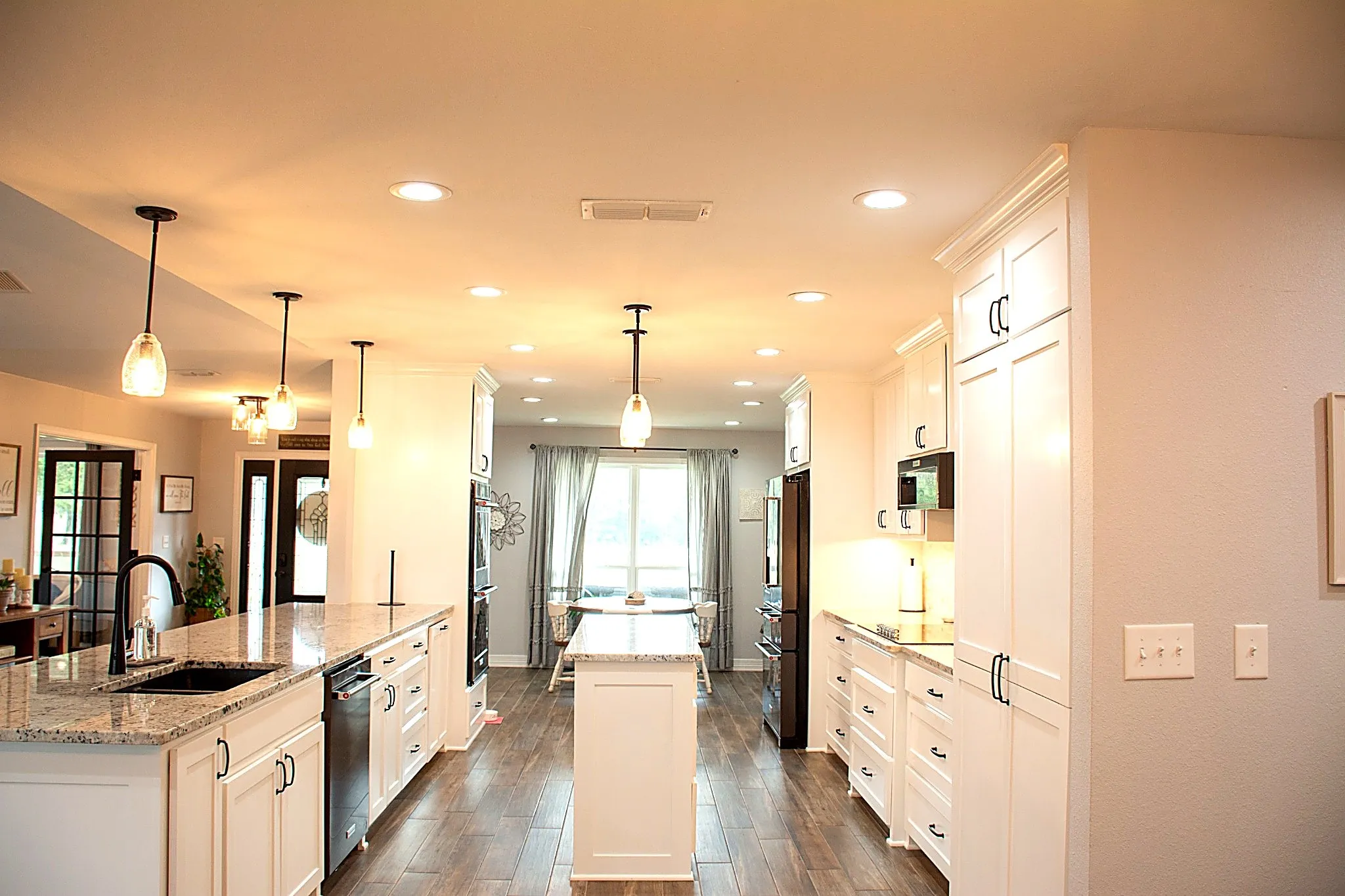 Spacious kitchen featuring an island, recessed lighting, white cabinetry, and granite countertops