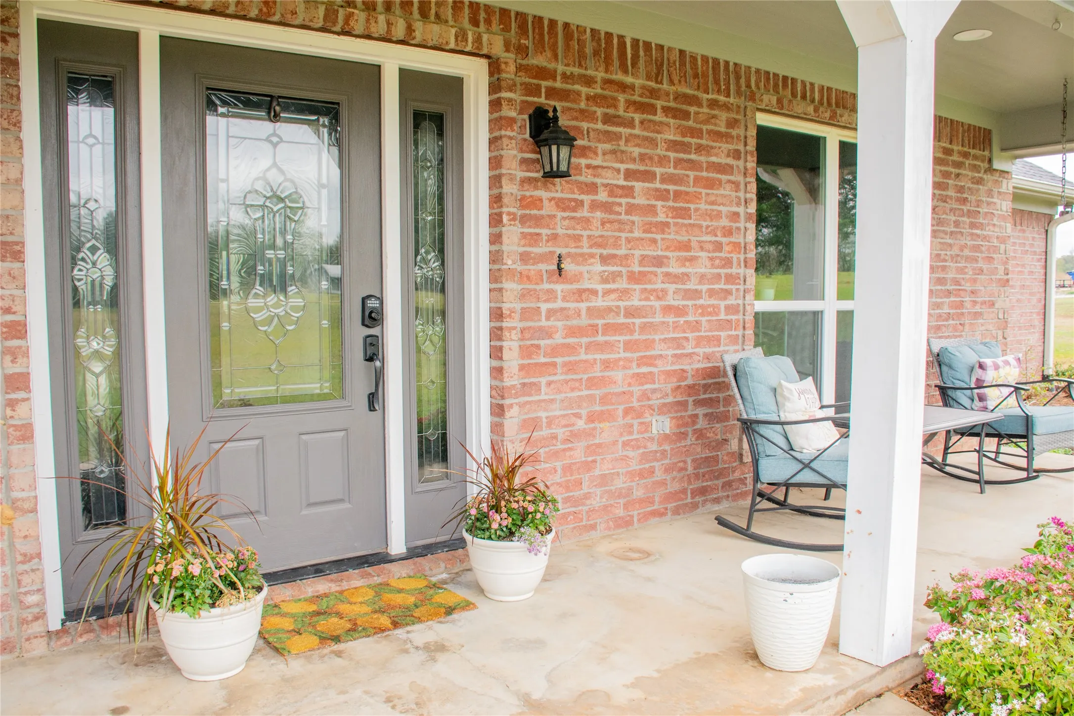 Brick exterior with a covered front porch, decorative glass entry door, and side-lite windows