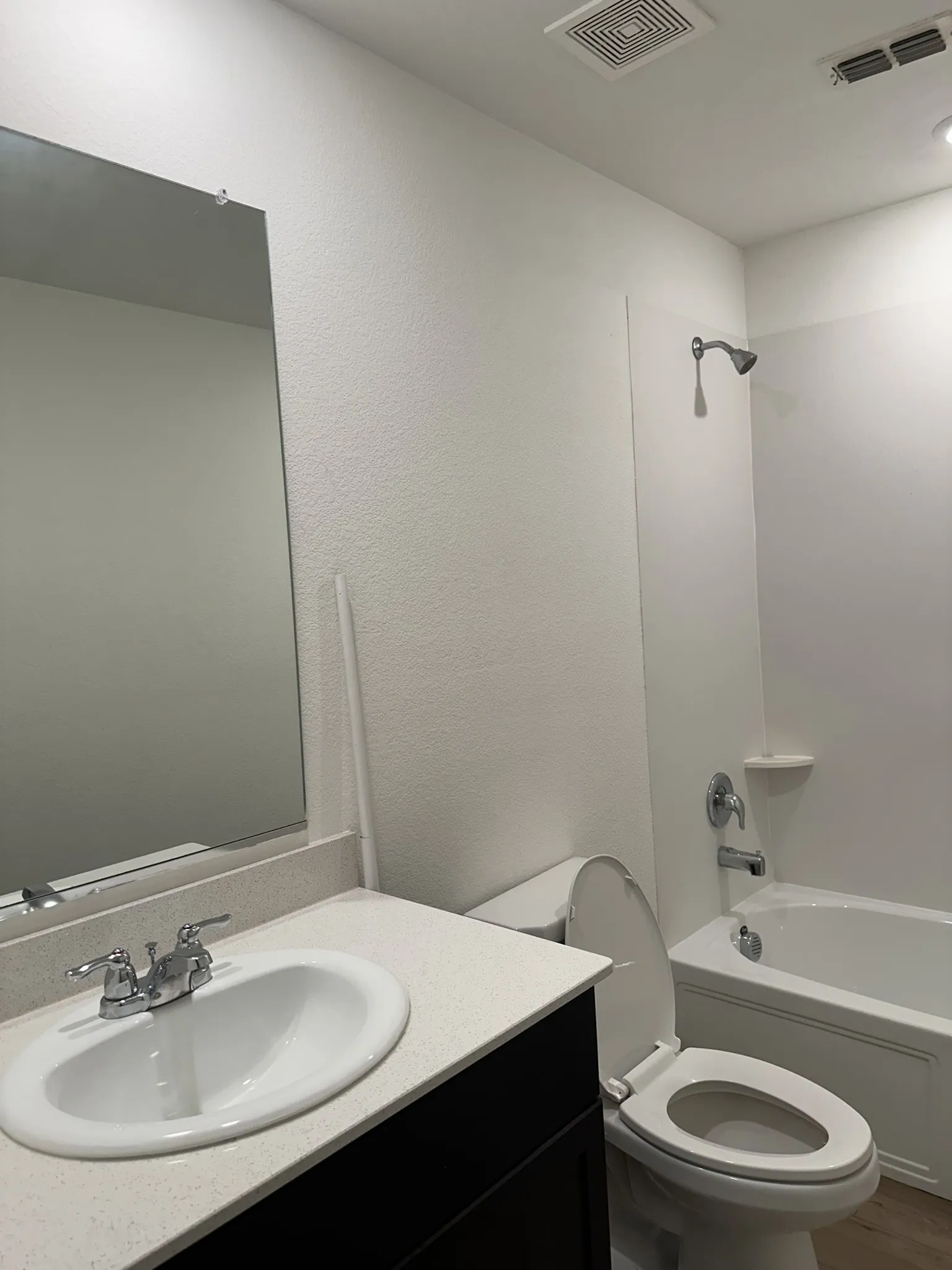 Bathroom with vanity, washtub / shower combination, and a textured wall