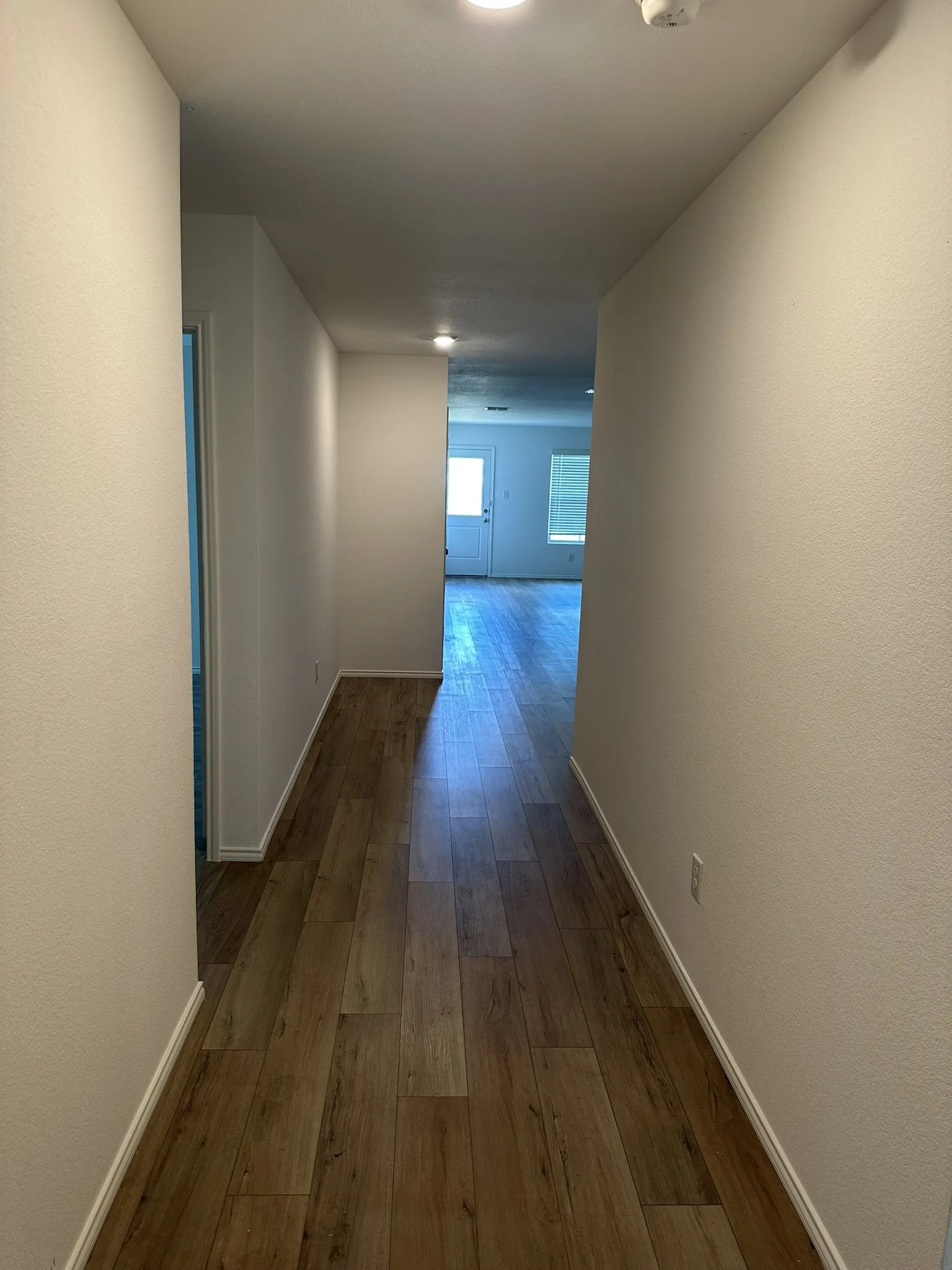 Hall featuring dark wood-style flooring and baseboards