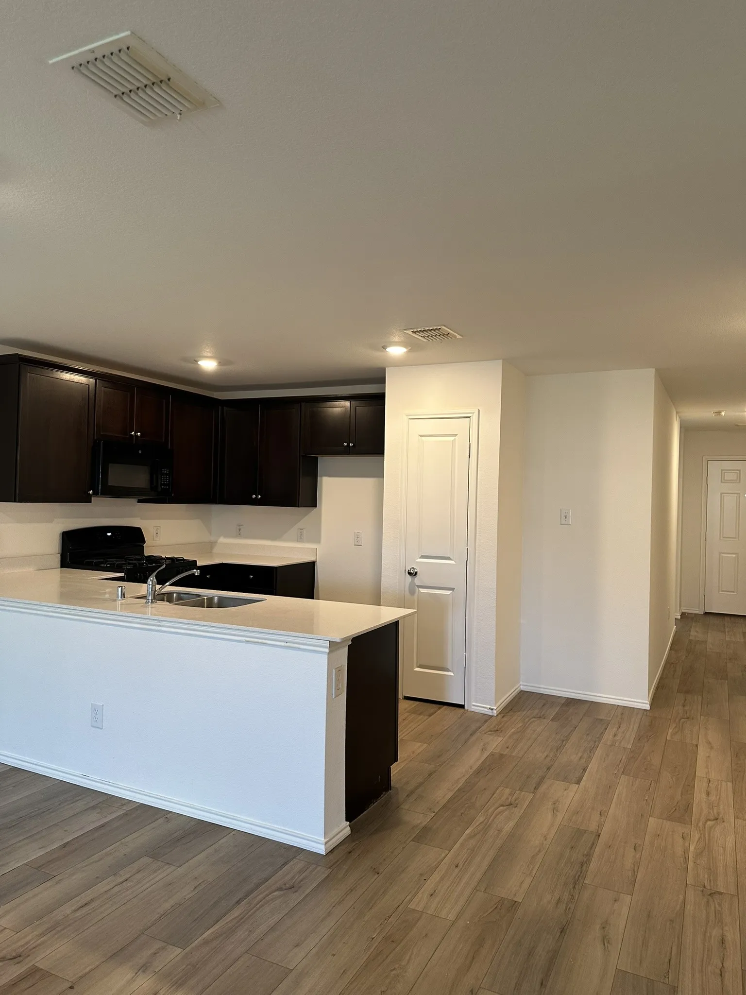 Kitchen with light wood-type flooring, black appliances, light countertops, a peninsula, and recessed lighting