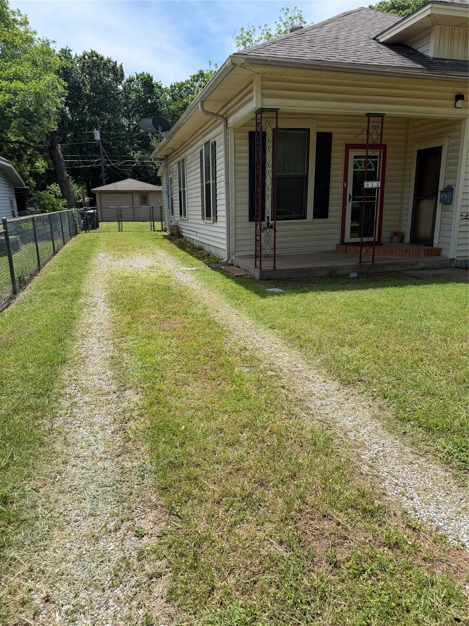Gravel driveway leads to detached garage behind fence.