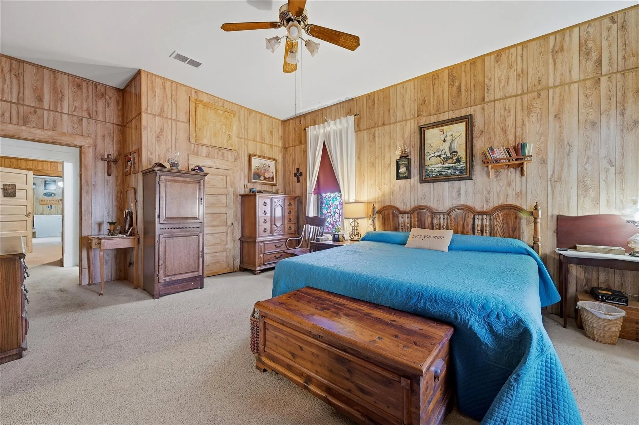Wood-finish paneled walls, ceiling fan with integrated lighting, and carpeted flooring