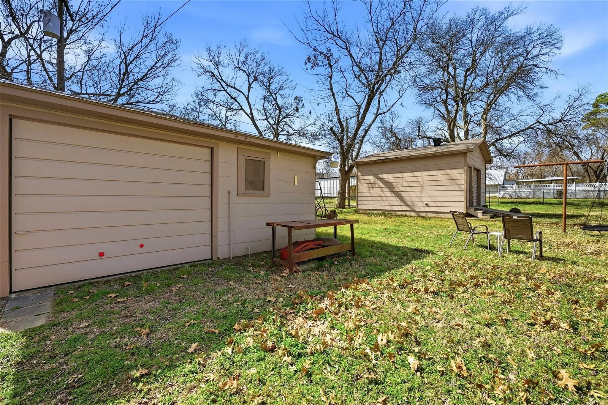 Detached garage with horizontal siding, a window, and a separate storage shed