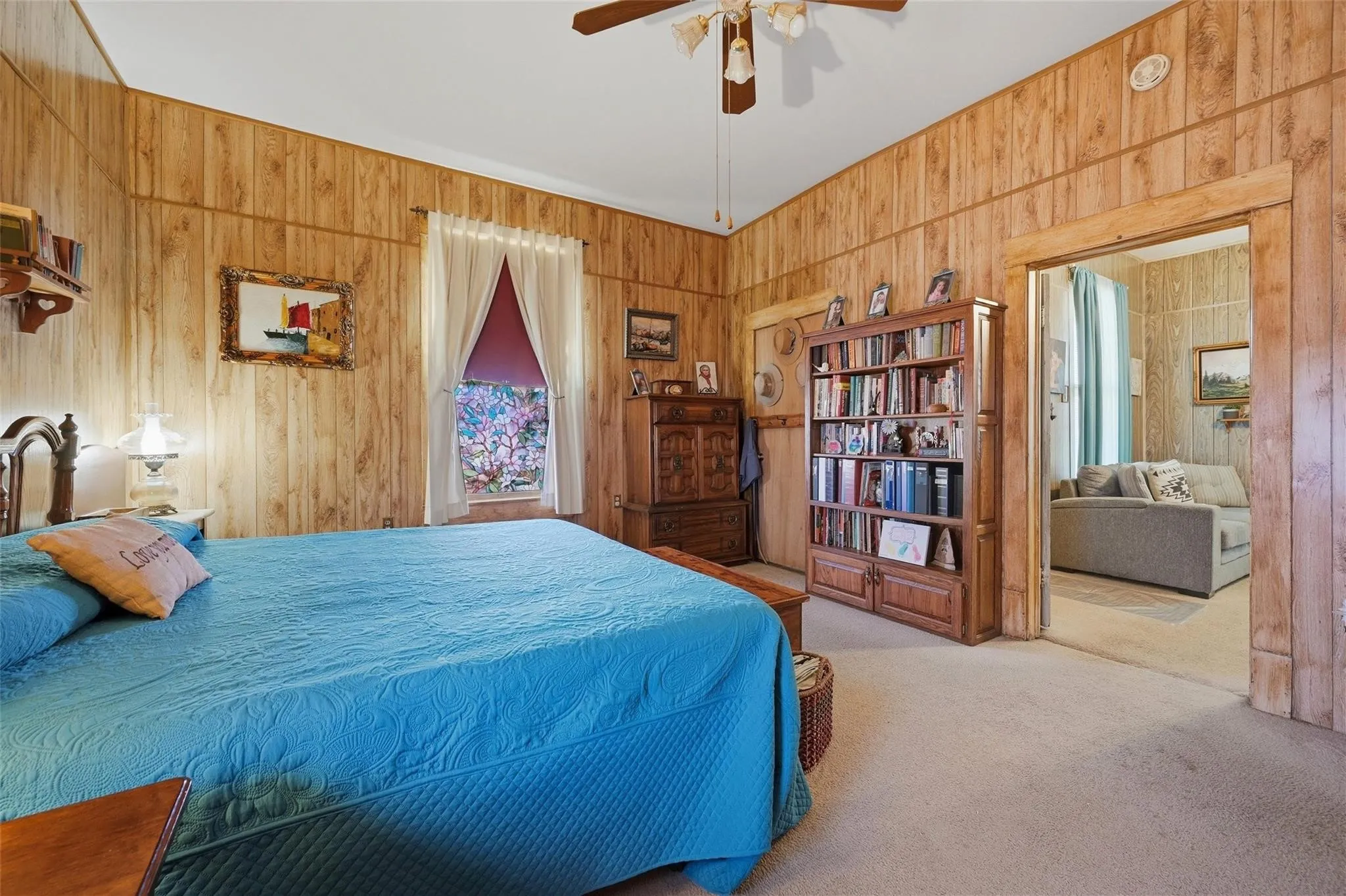 Wood paneling throughout, ceiling fan, and carpeted flooring