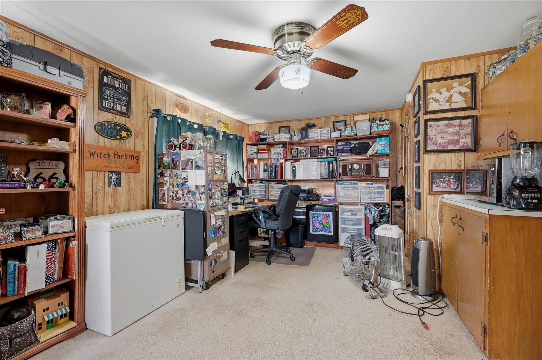 Wood paneling throughout, wood-finish ceiling fan with integrated lighting, built-in wooden shelving, and wall-mounted cabinetry