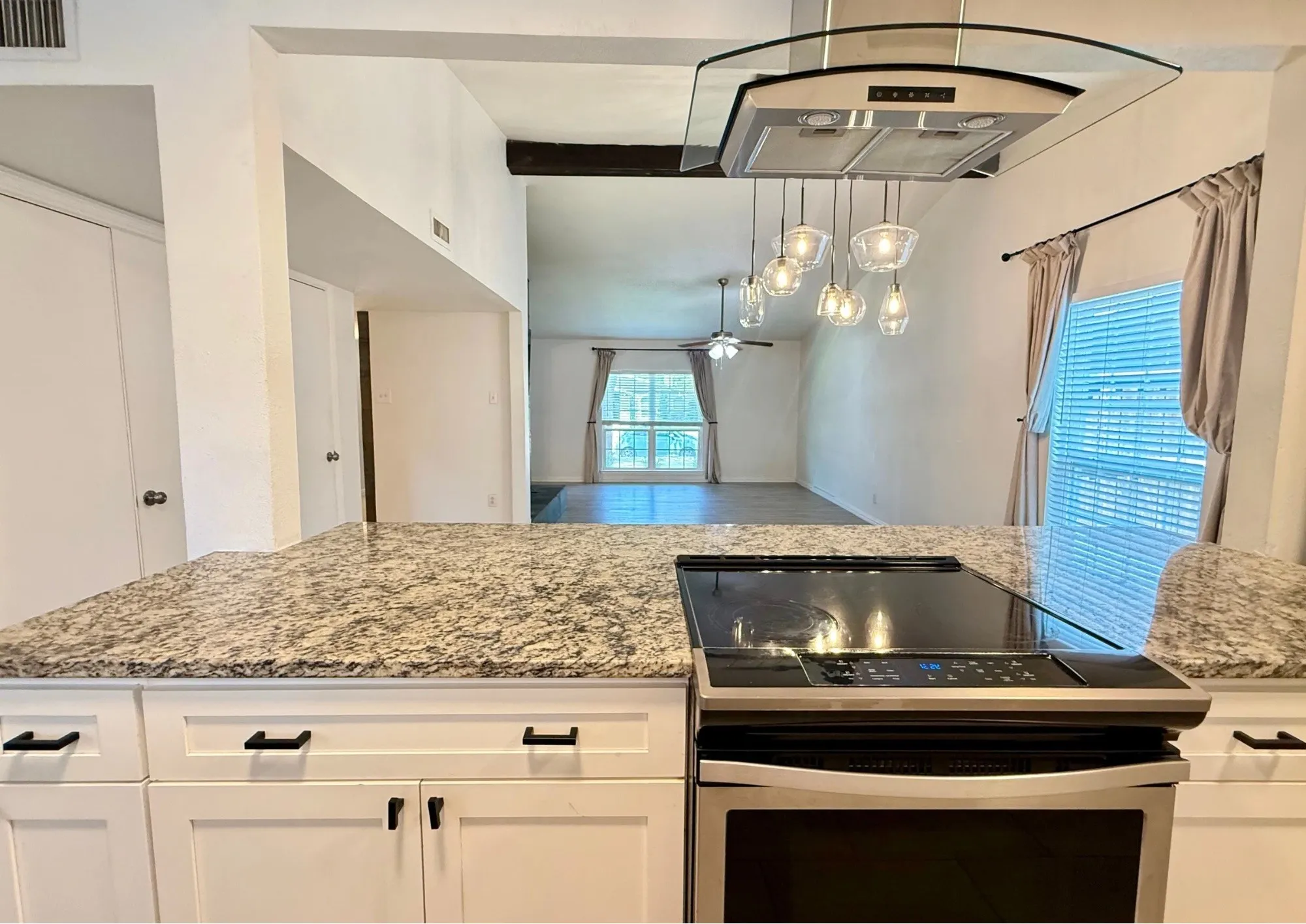 Kitchen island with a granite countertop, built-in cooktop, and stainless steel oven