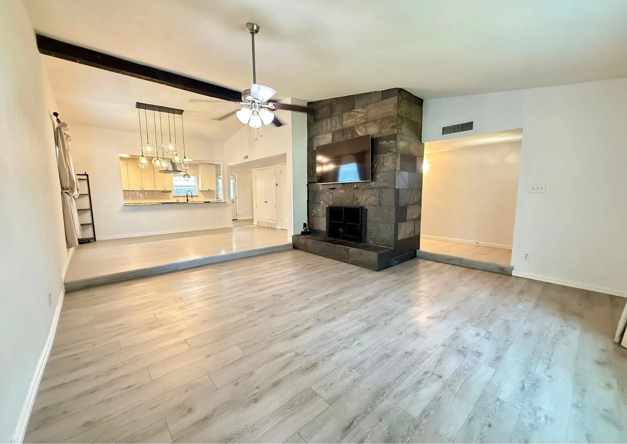 Living area with wood-finish flooring, stone-clad fireplace, and vaulted ceilings
