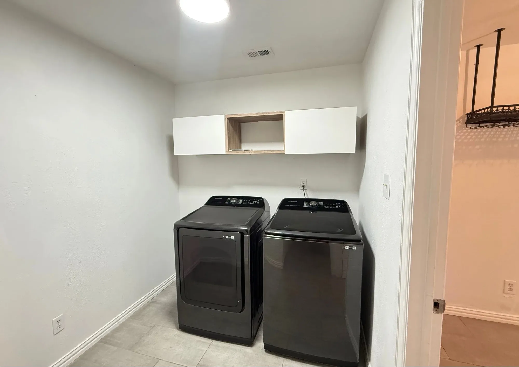 Laundry area with light-toned tiled flooring and recessed lighting