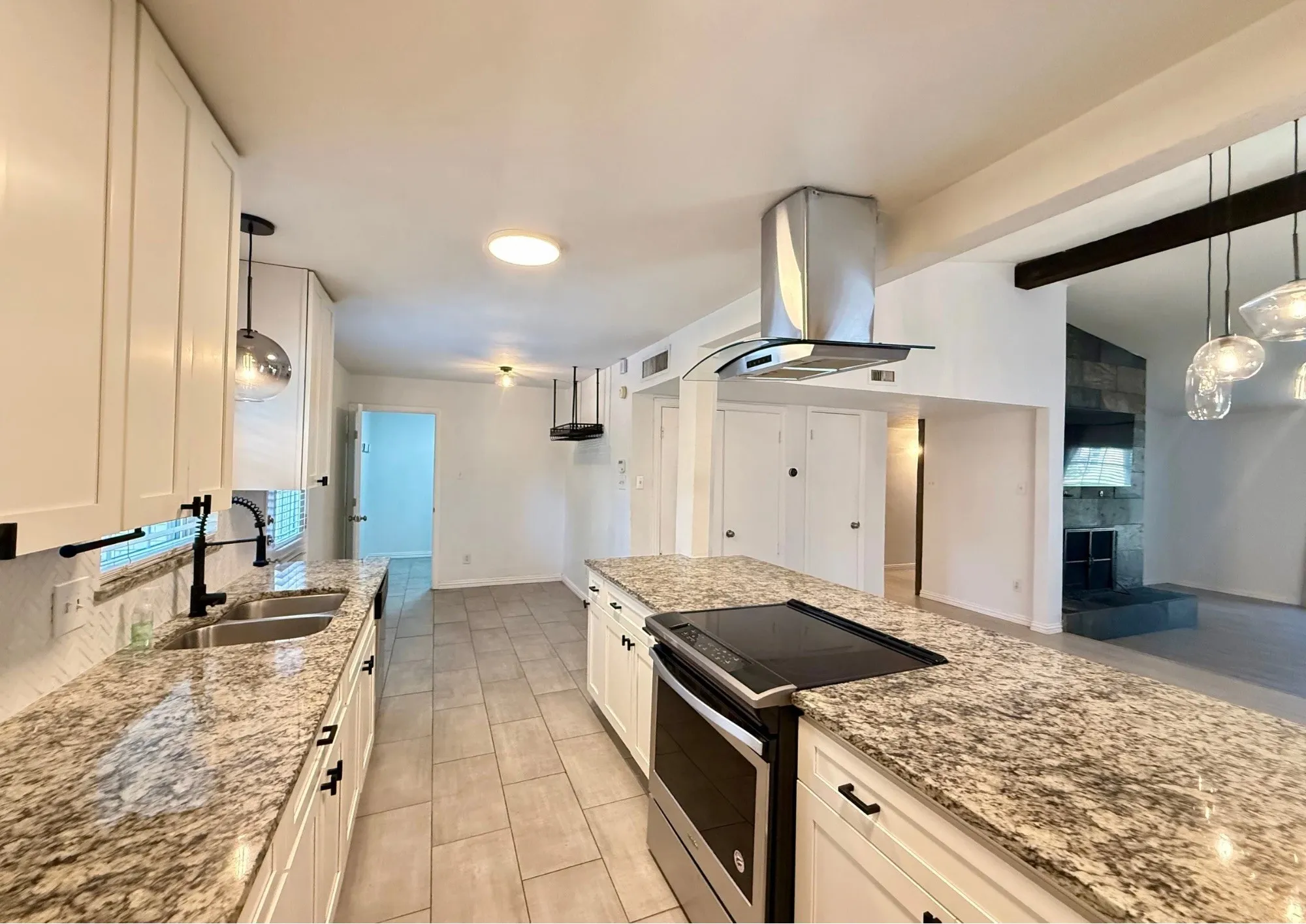 Kitchen featuring granite countertops, a built-in range, stainless steel range hood, white cabinetry, and tile flooring