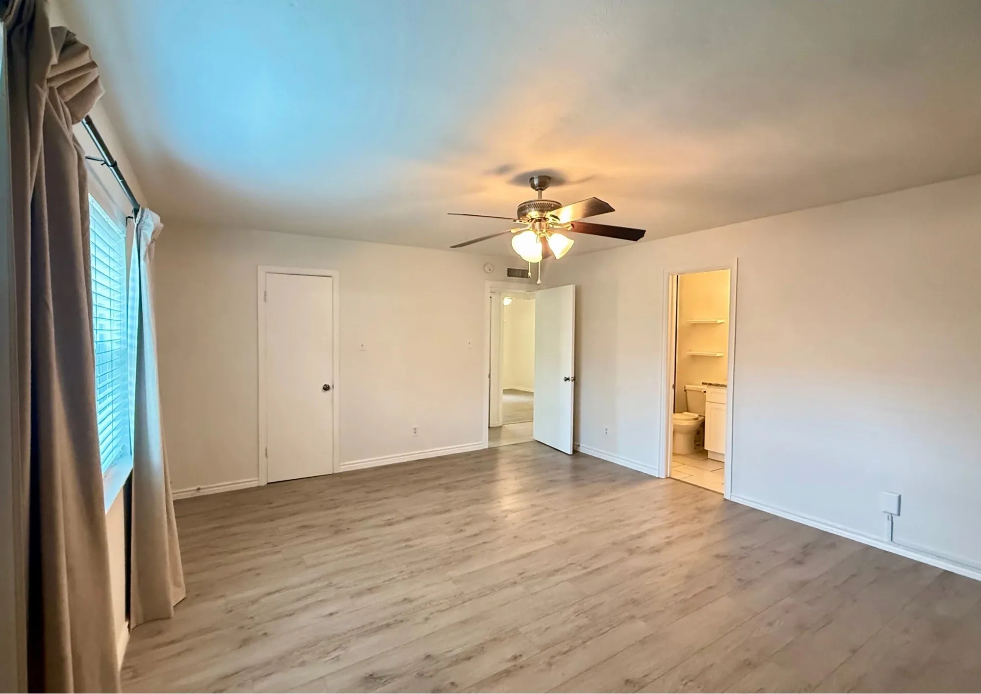 Spacious room featuring wood-finish flooring, a ceiling fan, and a window with blinds