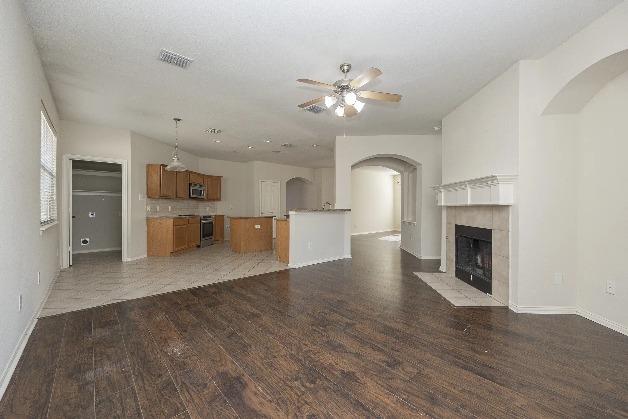 Living area with dark wood-finish flooring, a tile fireplace, and an arched entry