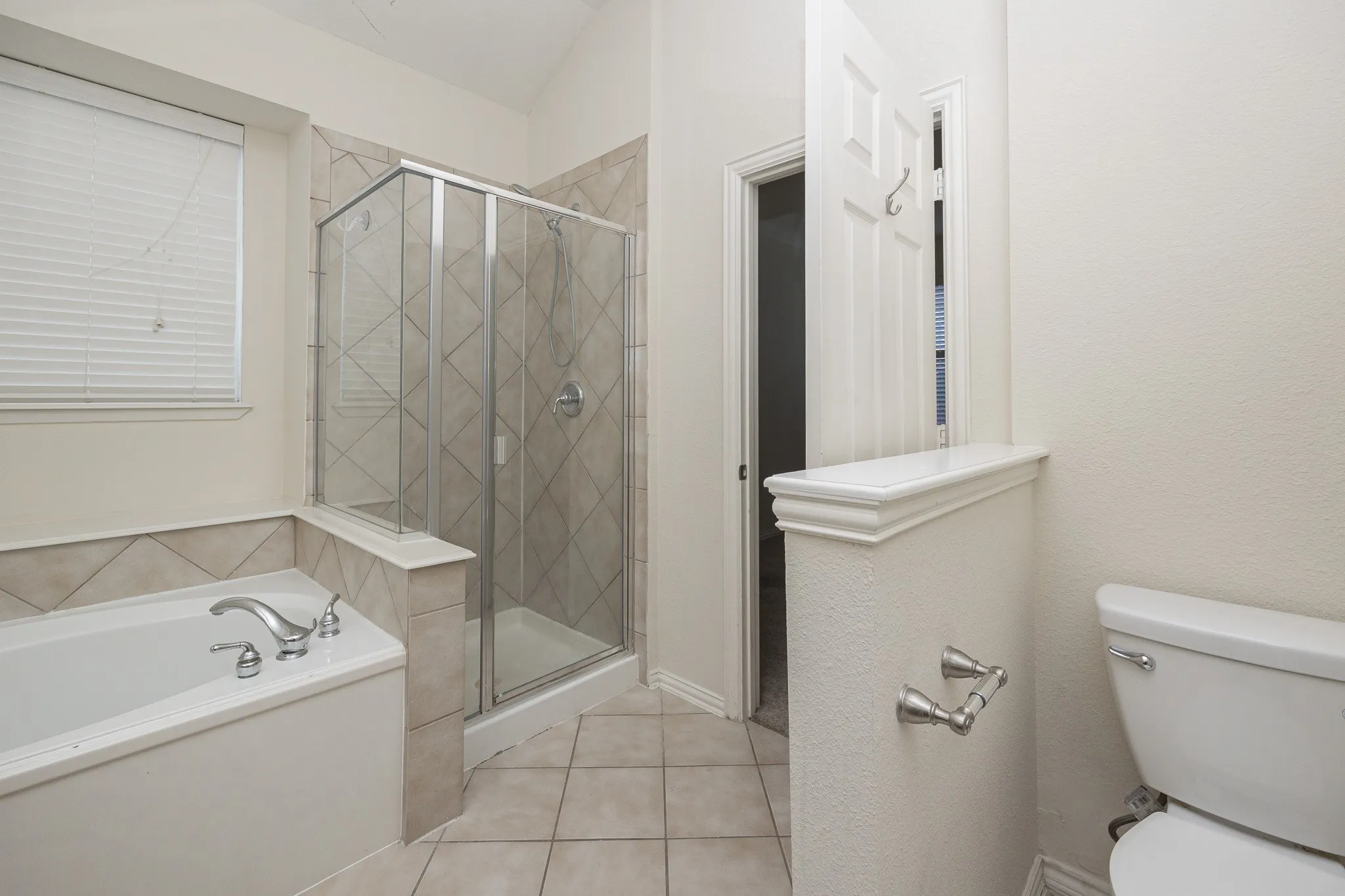 Built-in tub with chrome fixtures, glass-enclosed shower with tile surround, and tile flooring