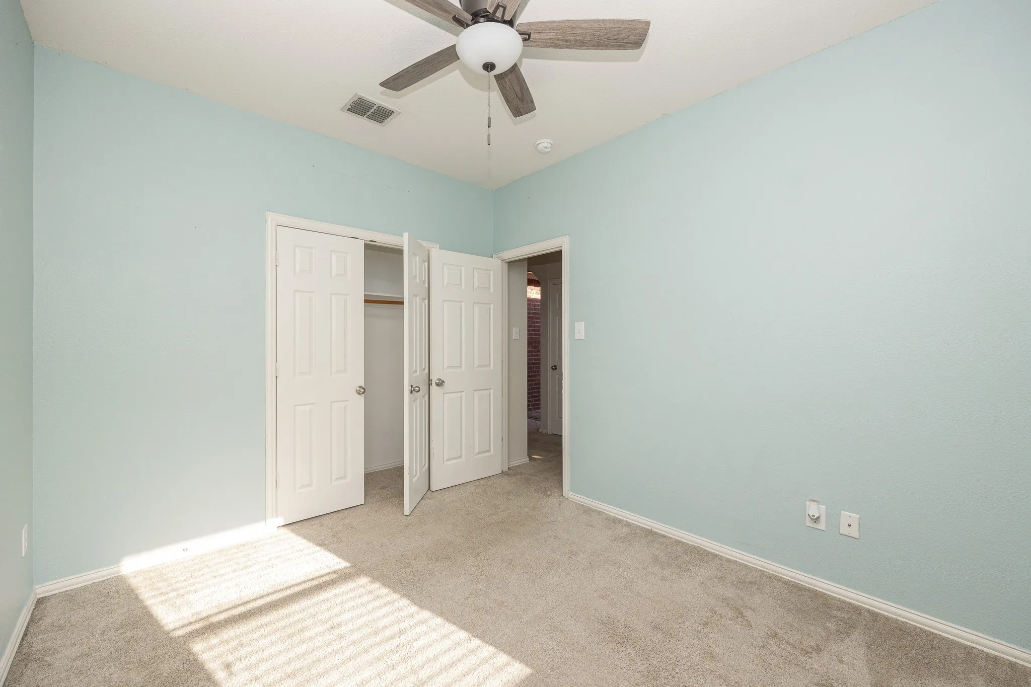 Soft blue walls complement plush gray carpeting