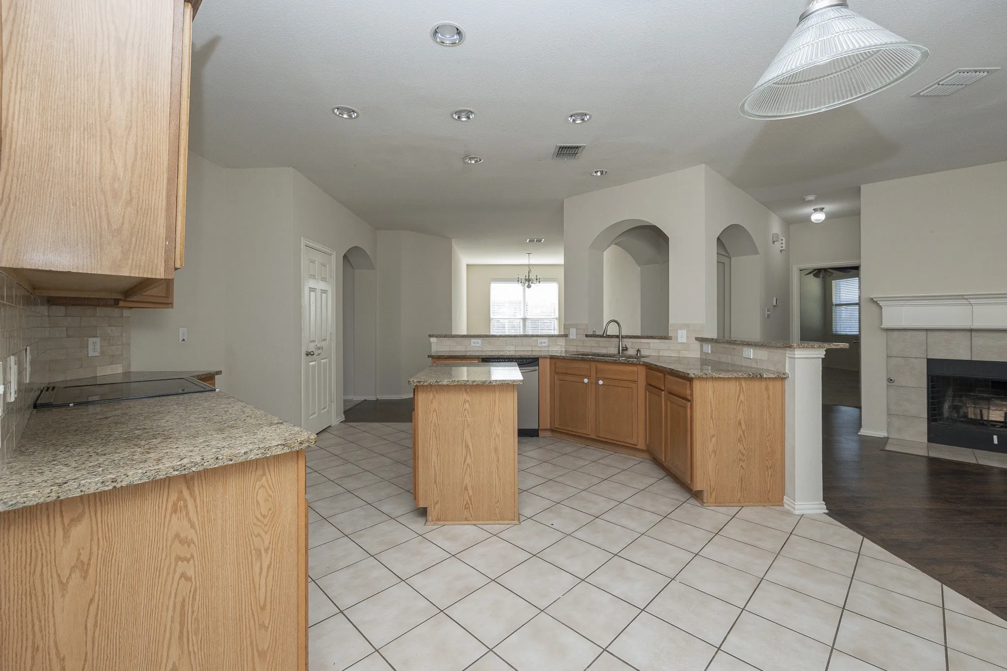 Kitchen featuring an integrated cooktop, granite countertops, wood cabinetry, stainless steel dishwasher, and recessed​​‌​​​​‌​​‌‌​‌‌​​​‌‌​‌​‌​‌​​​‌​​ lighting