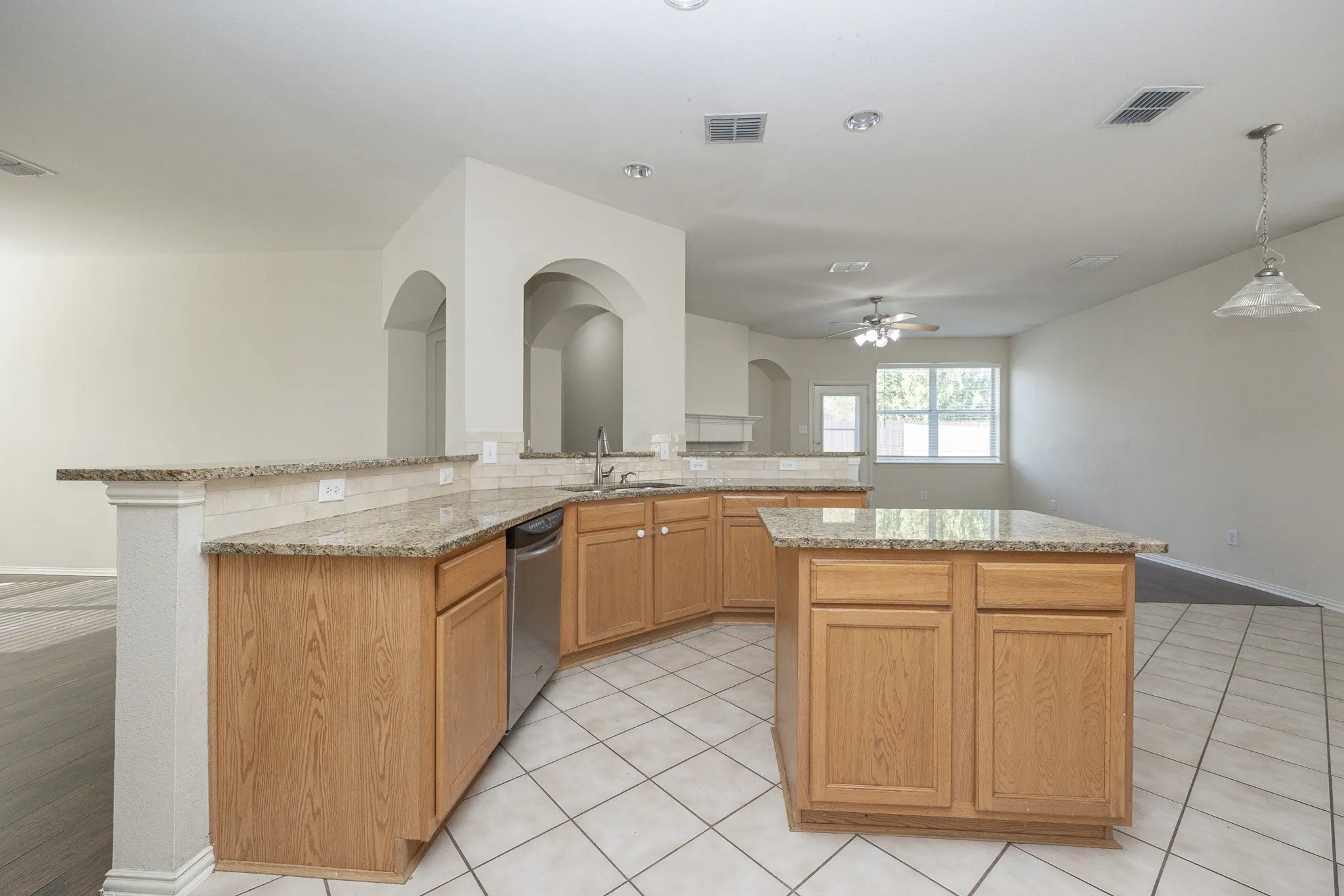 Kitchen featuring a central island, light wood-finish cabinetry, light-toned countertops, and a stainless steel dishwasher