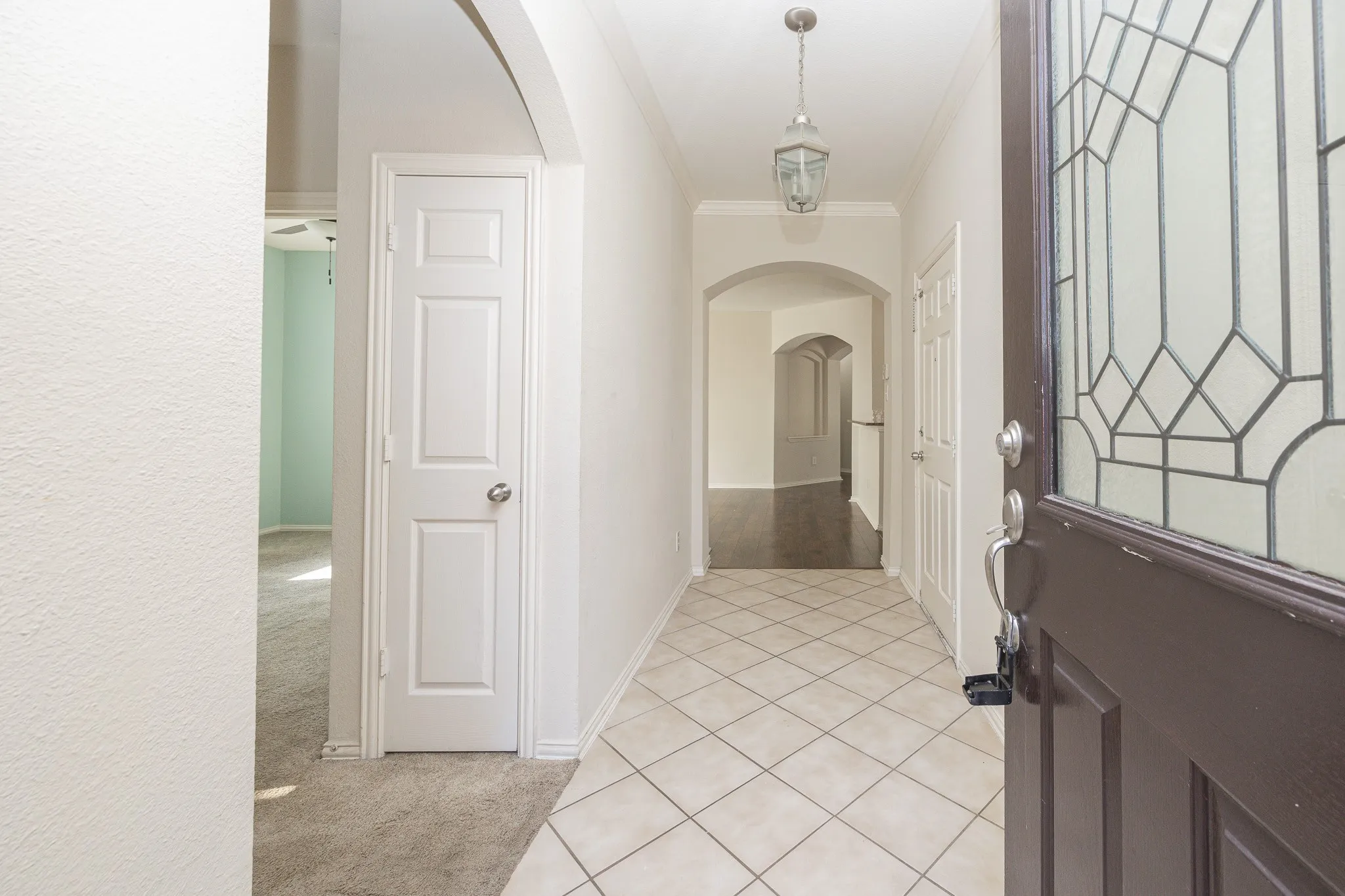 Entryway featuring diamond-patterned tile flooring, an arched doorway, and a decorative pendant light fixture