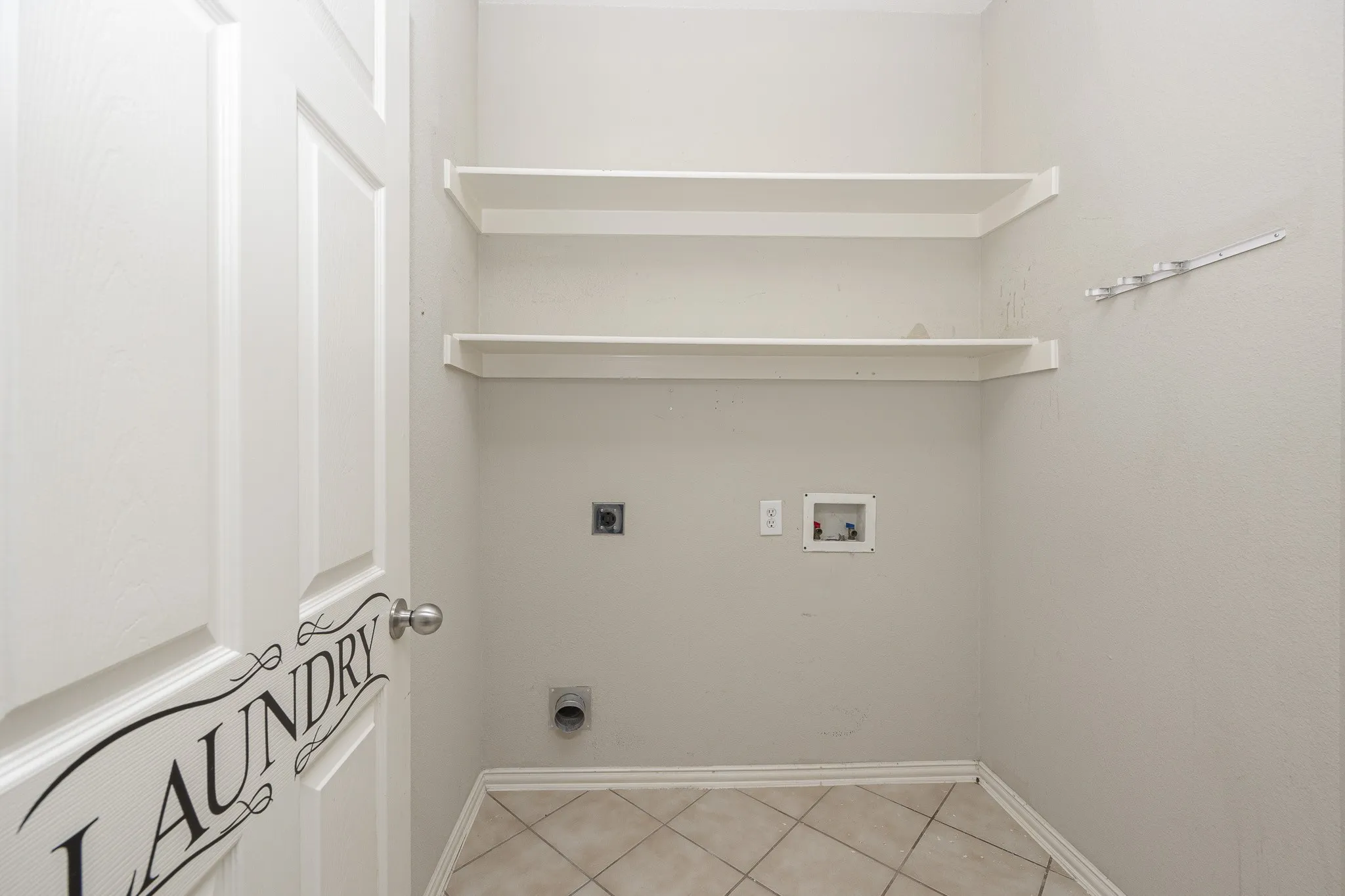 Tile flooring, two integrated wall shelves, laundry hookups, and a panel door