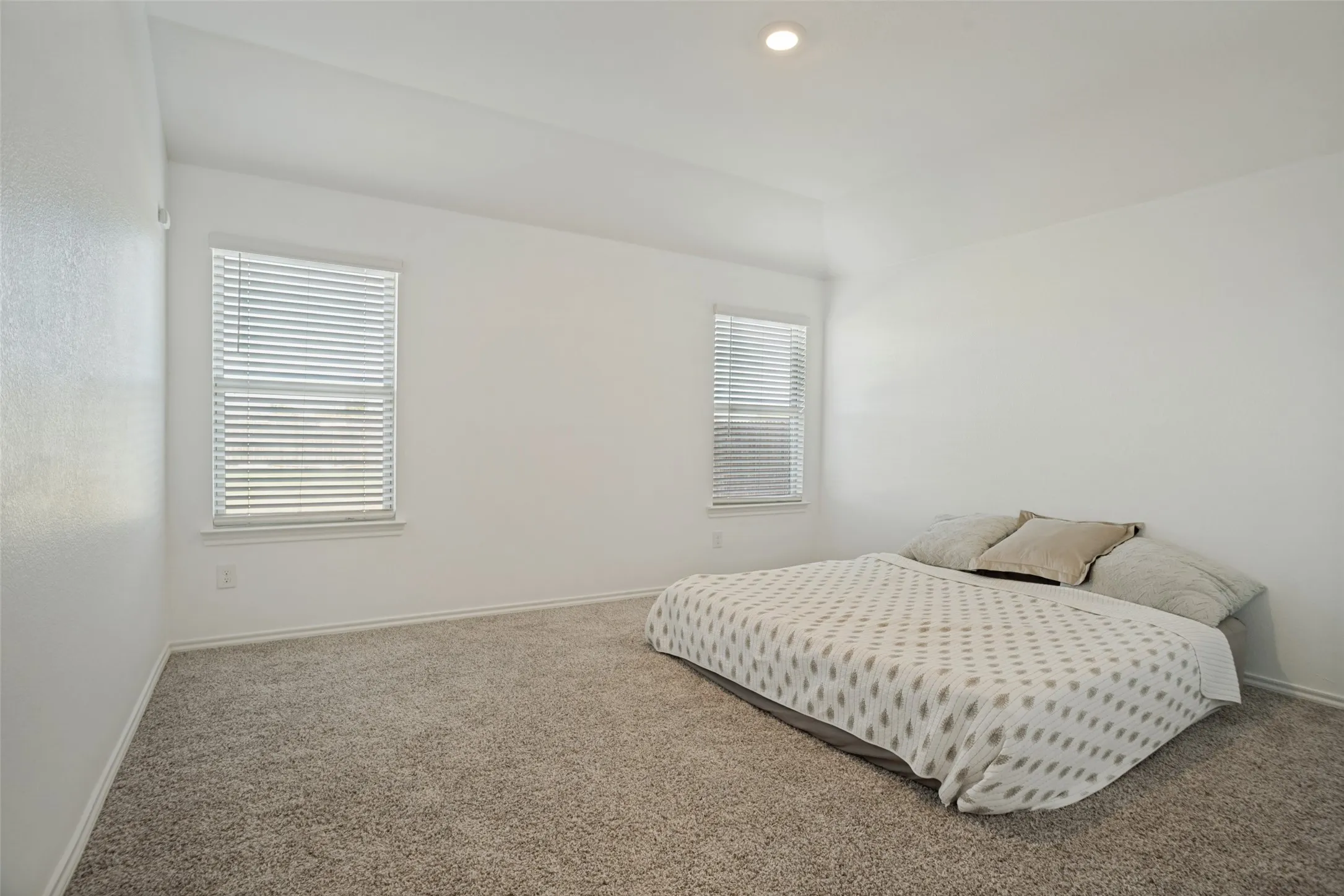 Plush carpeting, two windows with blinds, recessed lighting, and white wall finishes