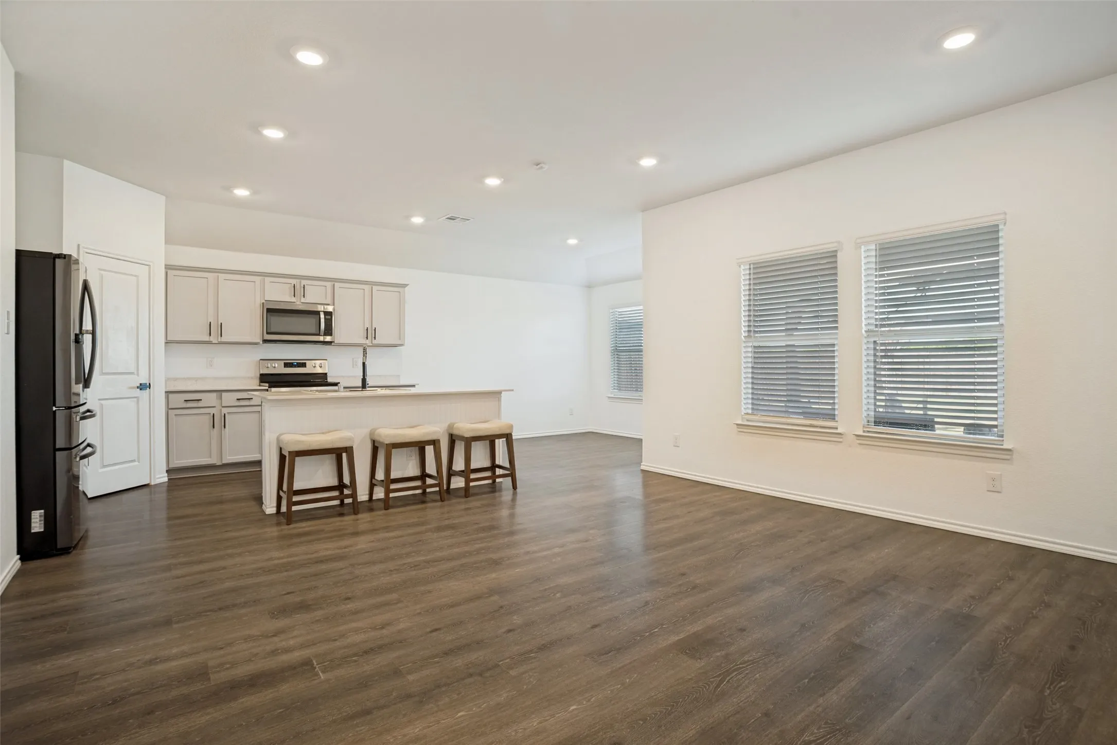 Open-concept layout with wood-finish flooring, recessed lighting, and a white kitchen island