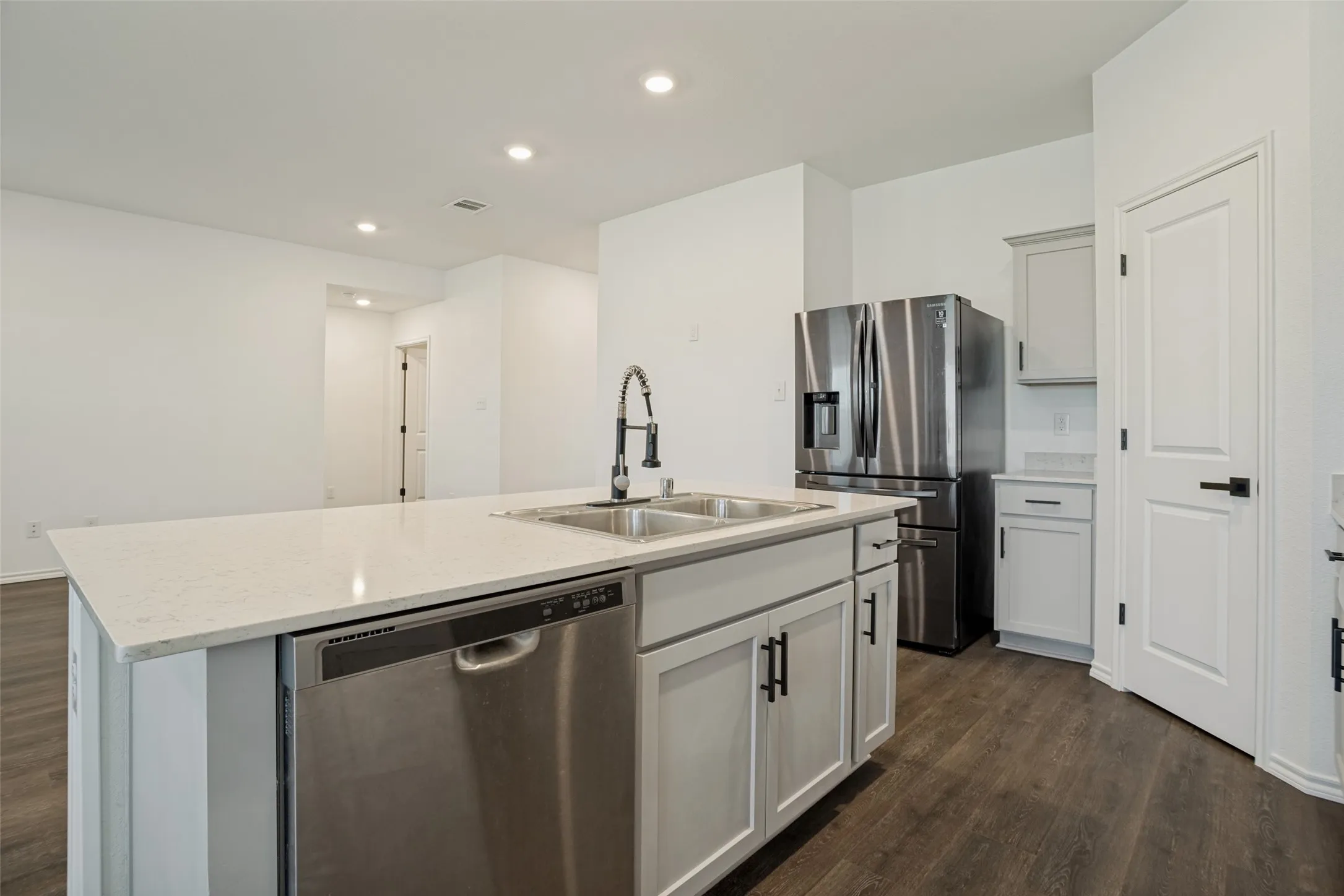 Kitchen island with a light-toned countertop, dual stainless steel sinks, and a stainless steel dishwasher
