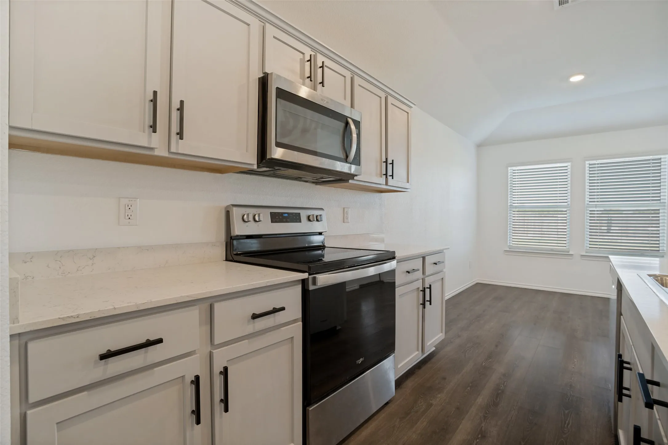 Kitchen featuring light-toned cabinetry, light countertops, stainless steel appliances, and wood-finish flooring