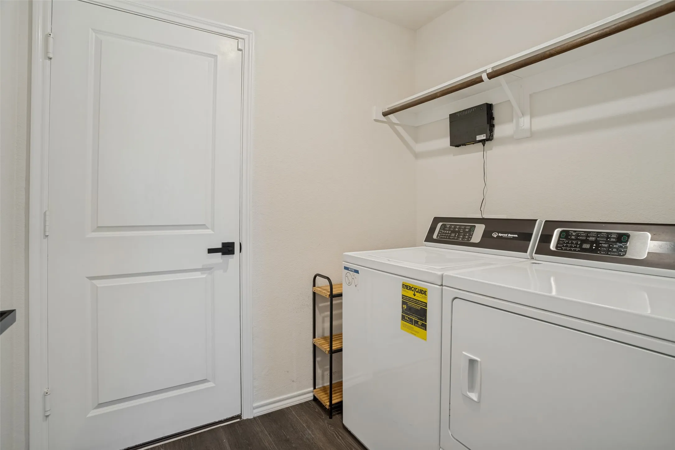 Laundry area with wood-finish flooring, white walls, and a built-in shelving unit