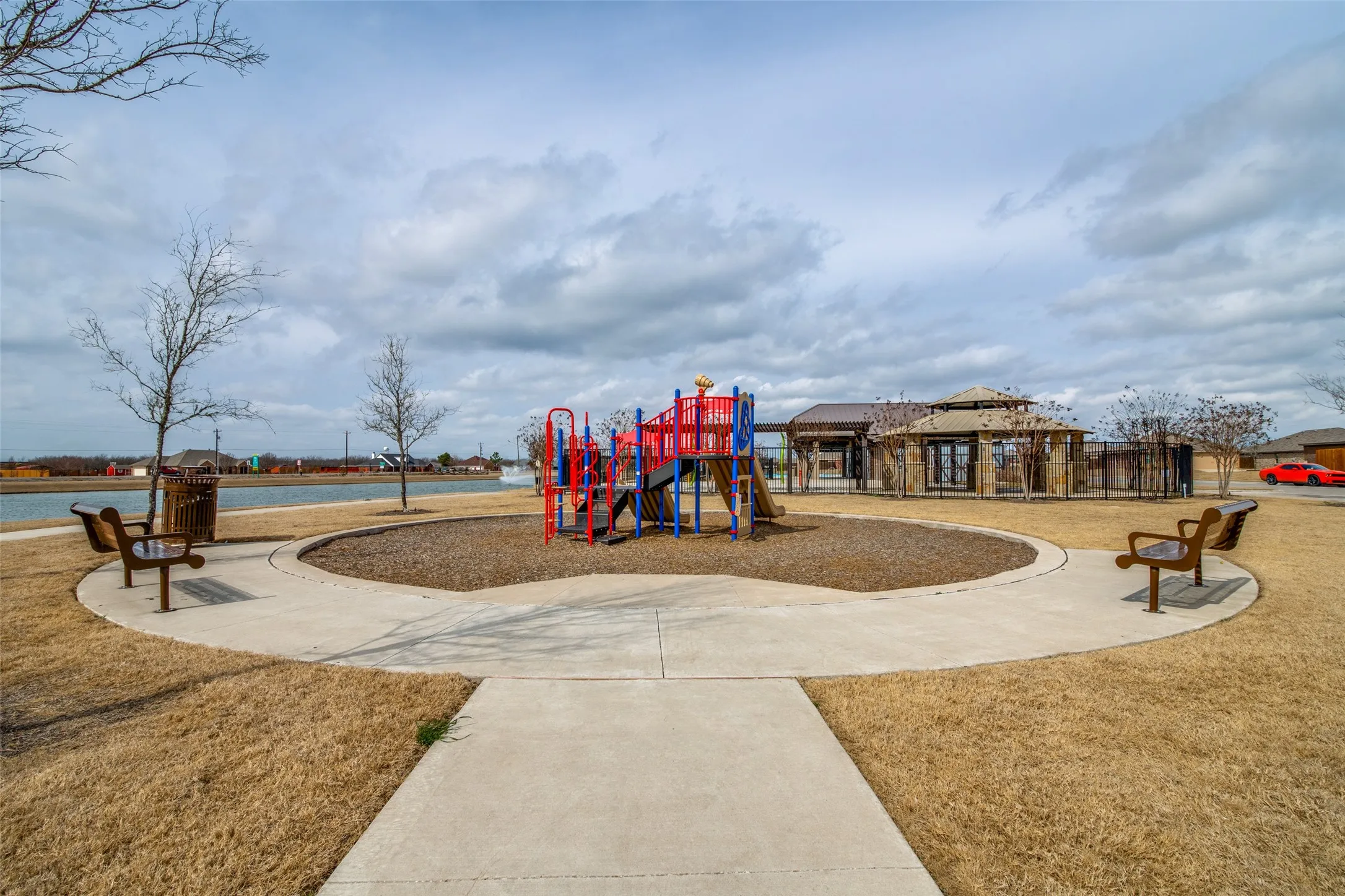 Recreational park area featuring a playground, multiple benches, and paved pathways