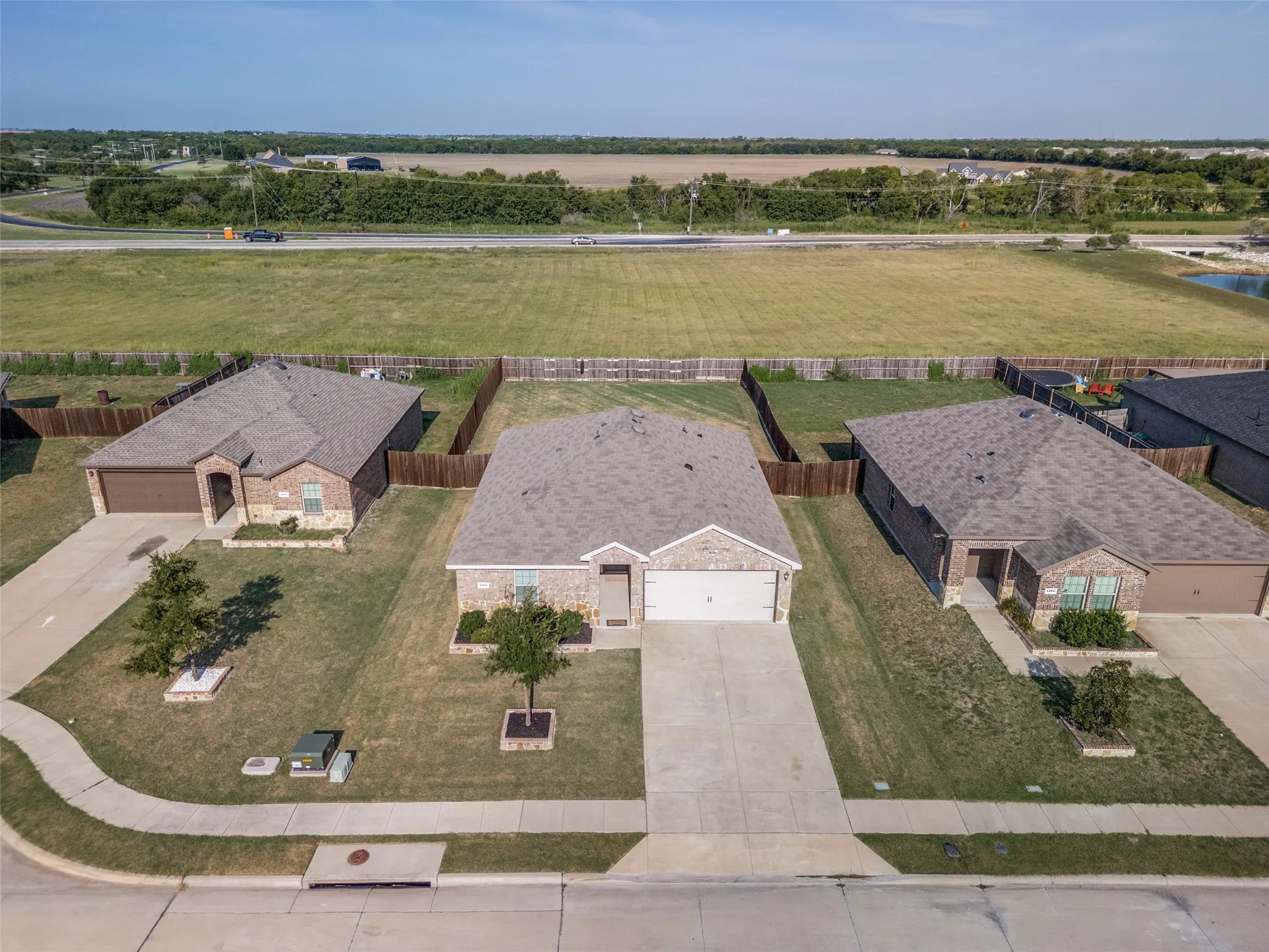 Brick and siding exterior, attached garage, concrete driveway, fenced backyard, and a paved street