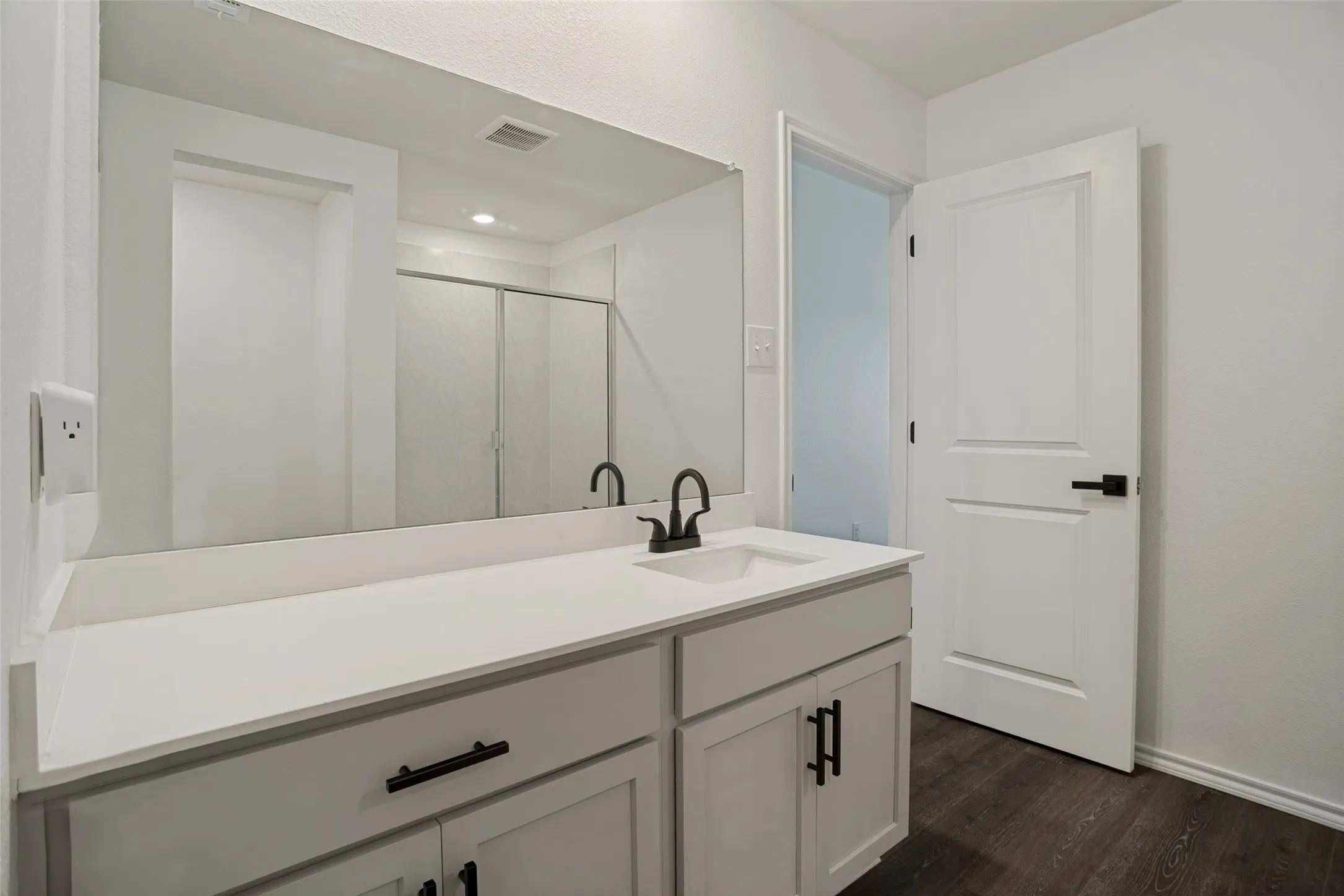 White vanity with integrated sink, matte black faucet, and white countertop