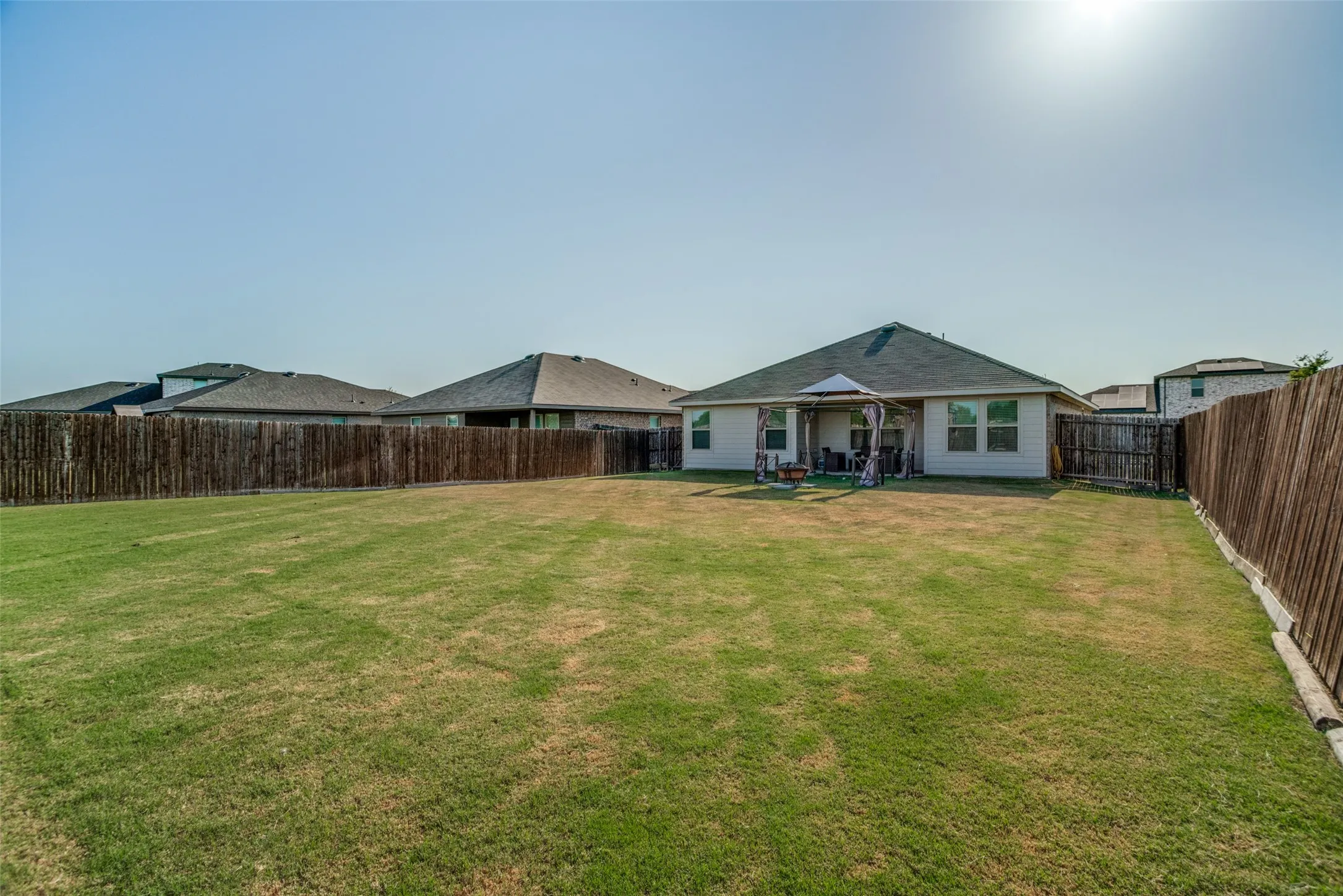 Expansive backyard with a covered patio, privacy fencing, and a manicured lawn