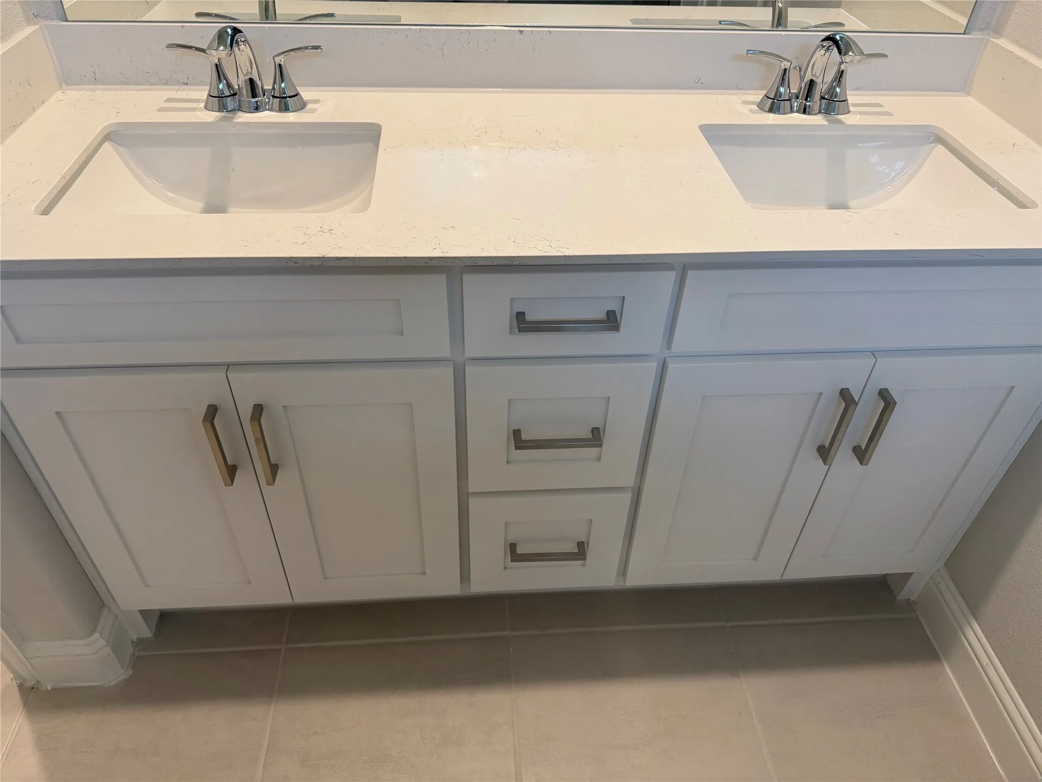 Dual vanity with integrated sinks and chrome fixtures, white cabinetry, and a light-toned countertop