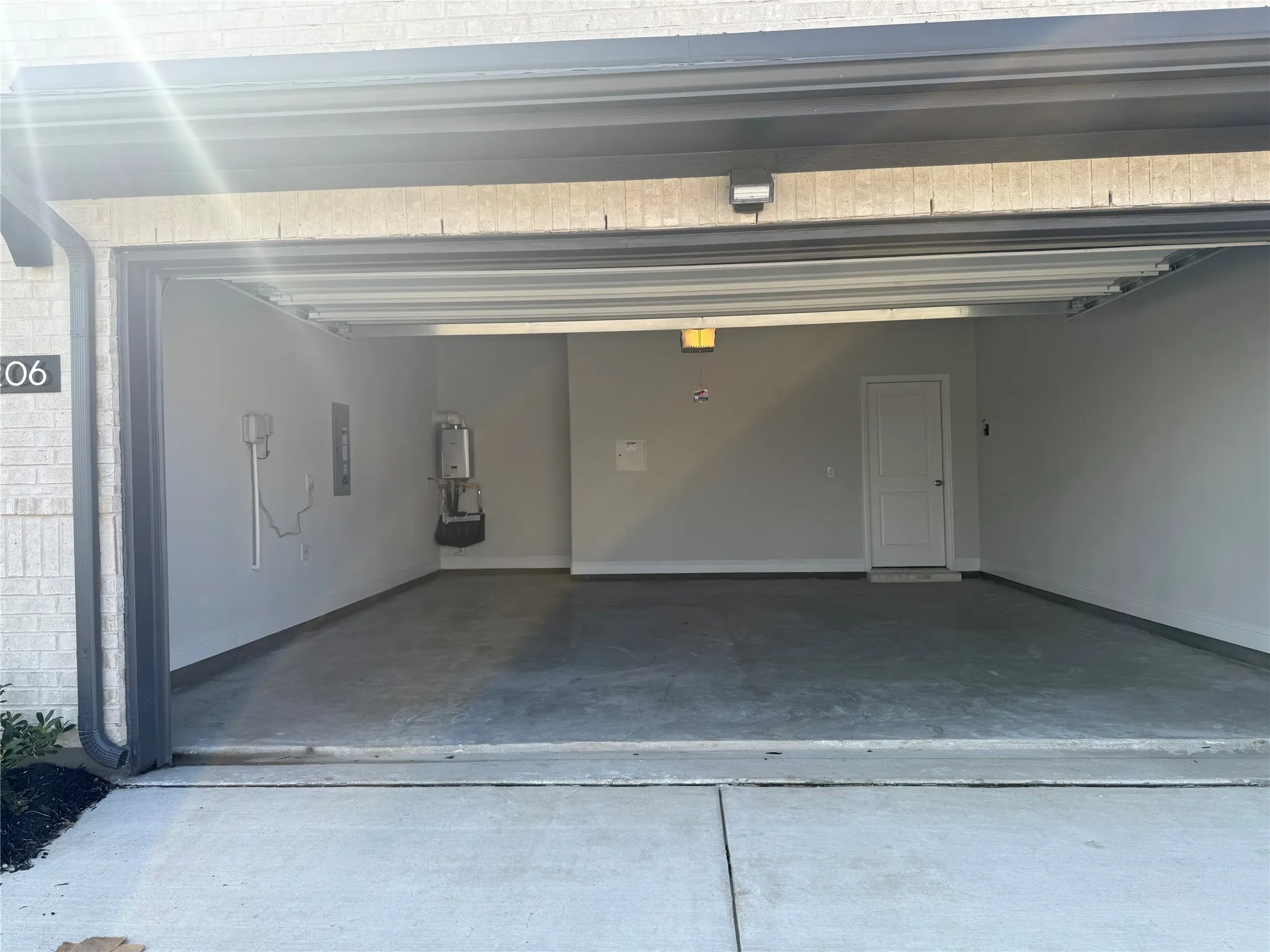 Spacious garage featuring concrete flooring, an interior access door, wall-mounted water heater, and overhead lighting
