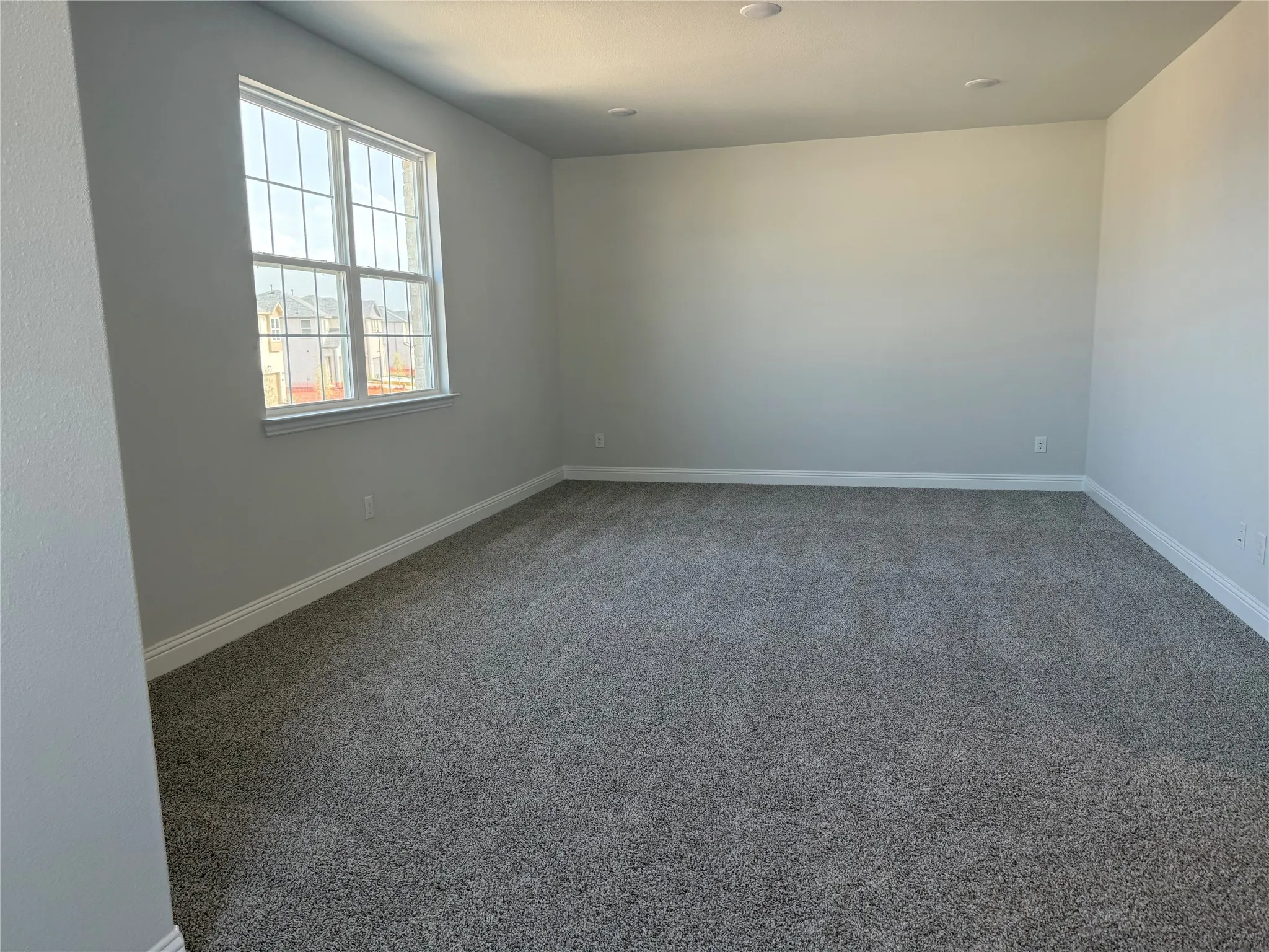 Recessed ceiling lighting, neutral gray wall paint, white trim, and gray carpet