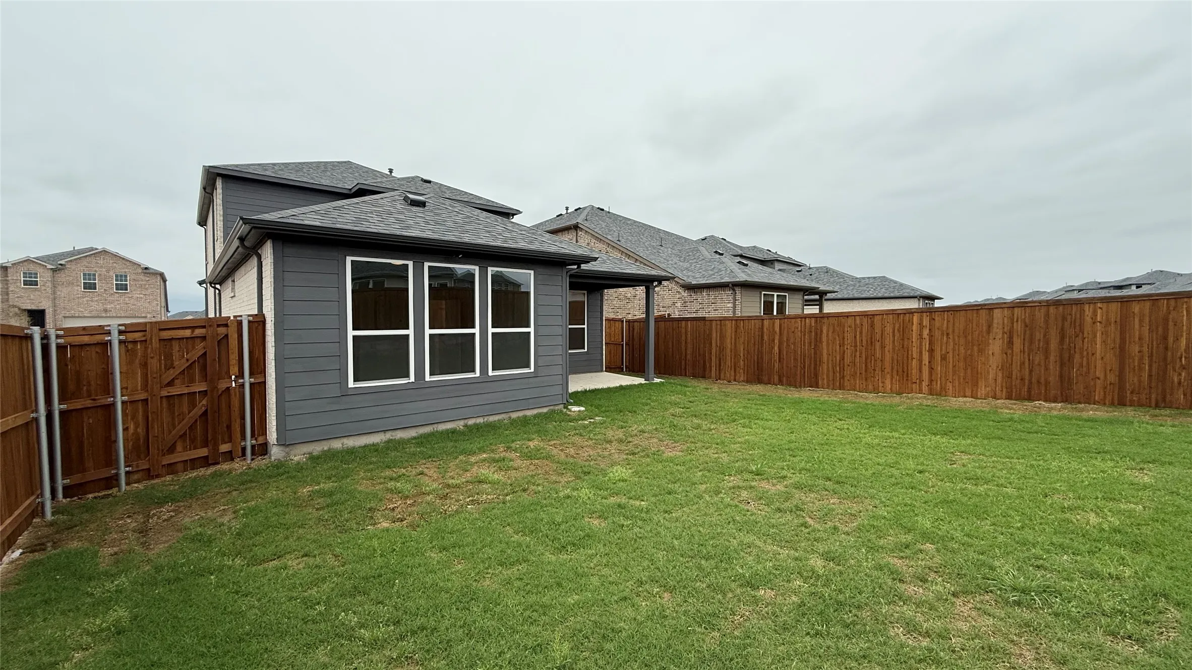 Expansive yard featuring a privacy fence, covered patio, and large windows
