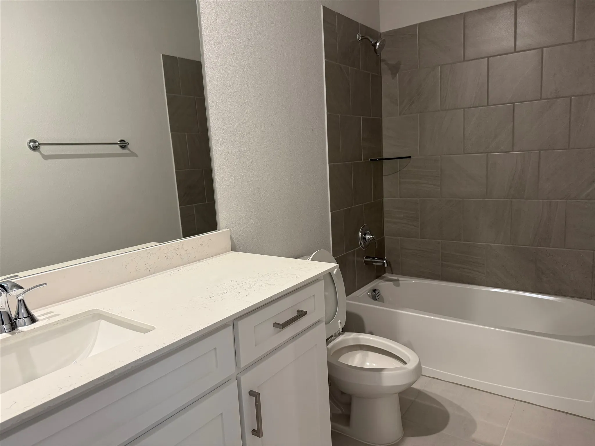 Bathroom featuring a vanity with an integrated sink, a built-in bathtub with a tile surround, and a chrome faucet and shower head
