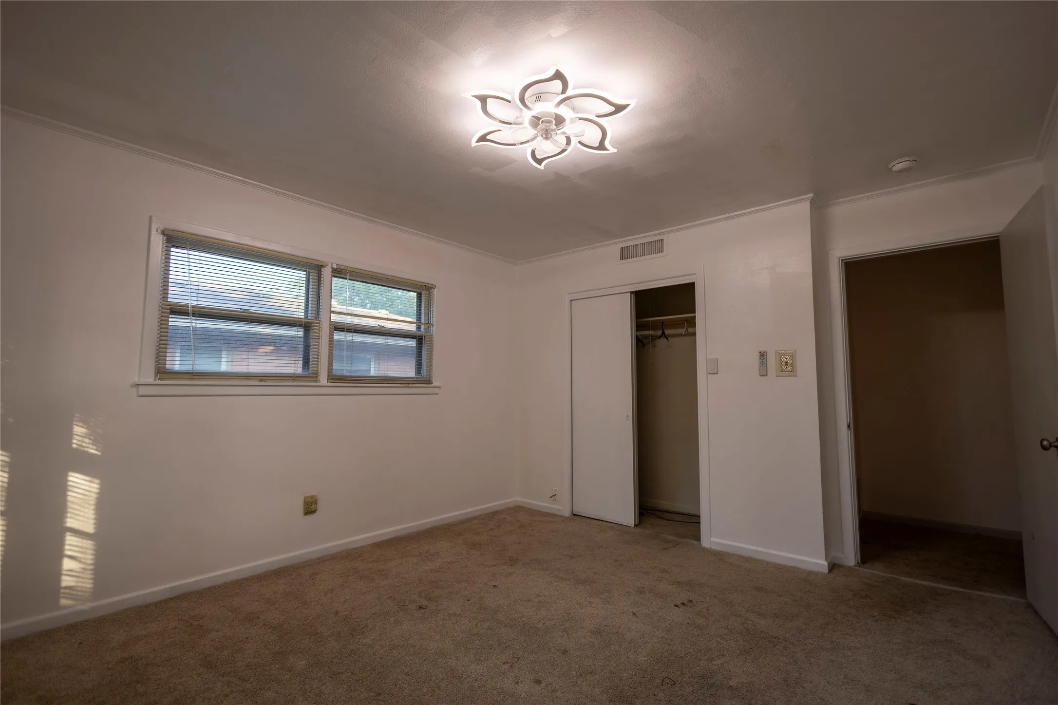 White painted walls, crown molding, and a decorative flush-mount ceiling light fixture