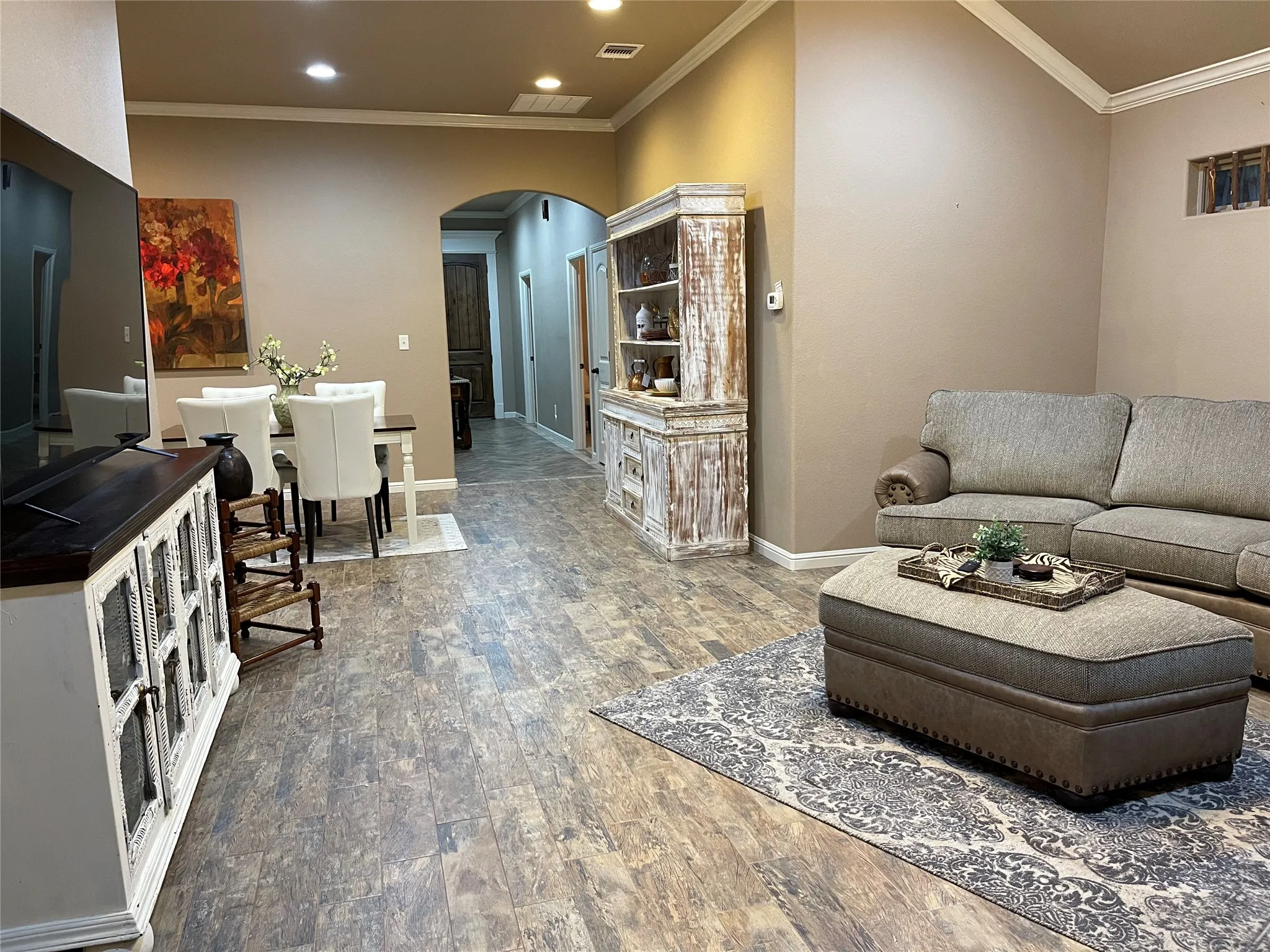 Open concept living area featuring wood-finish flooring, recessed lighting, and crown molding