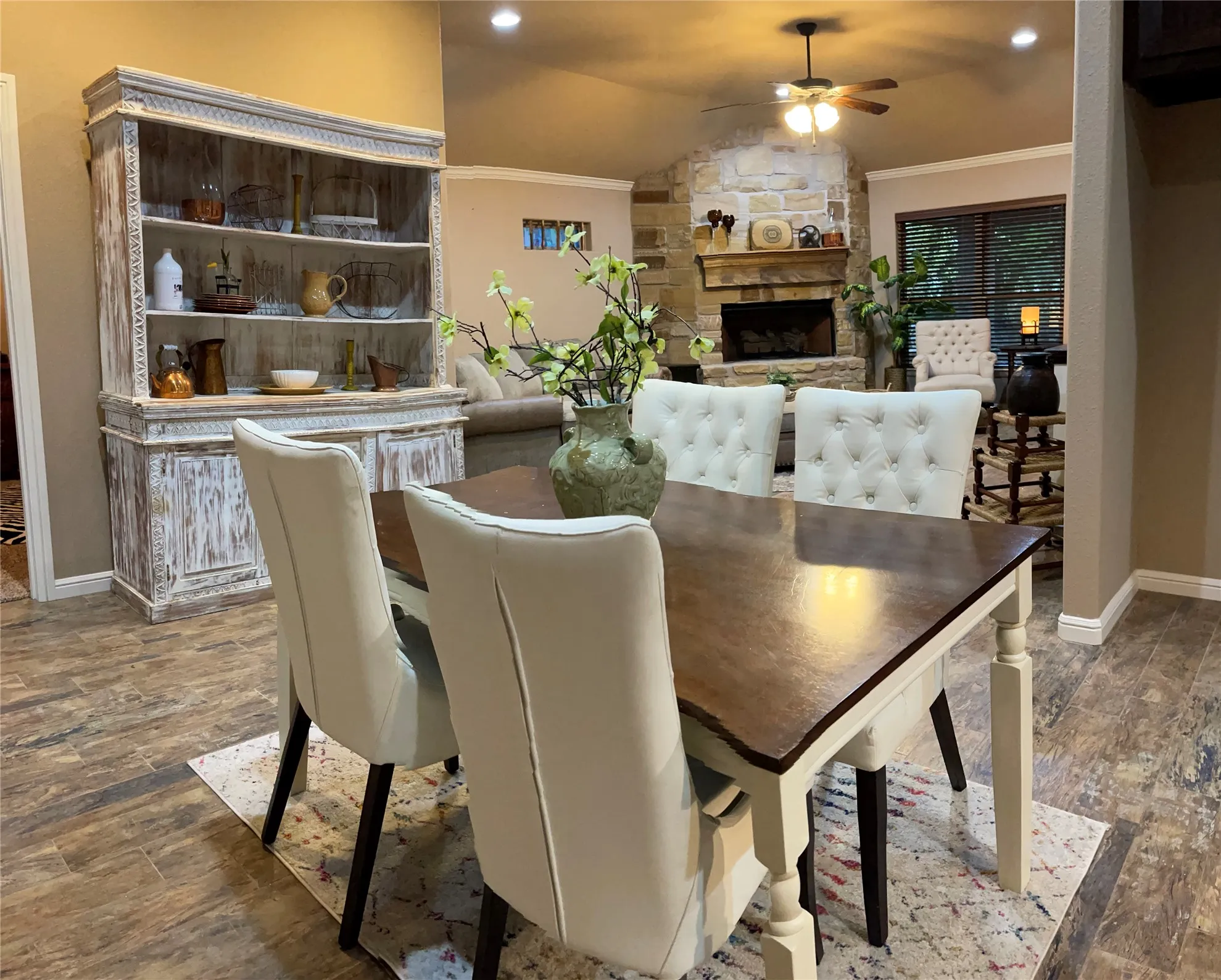 Open-concept living space featuring wood-finish flooring, recessed lighting, and a stone-clad fireplace with a wood mantel