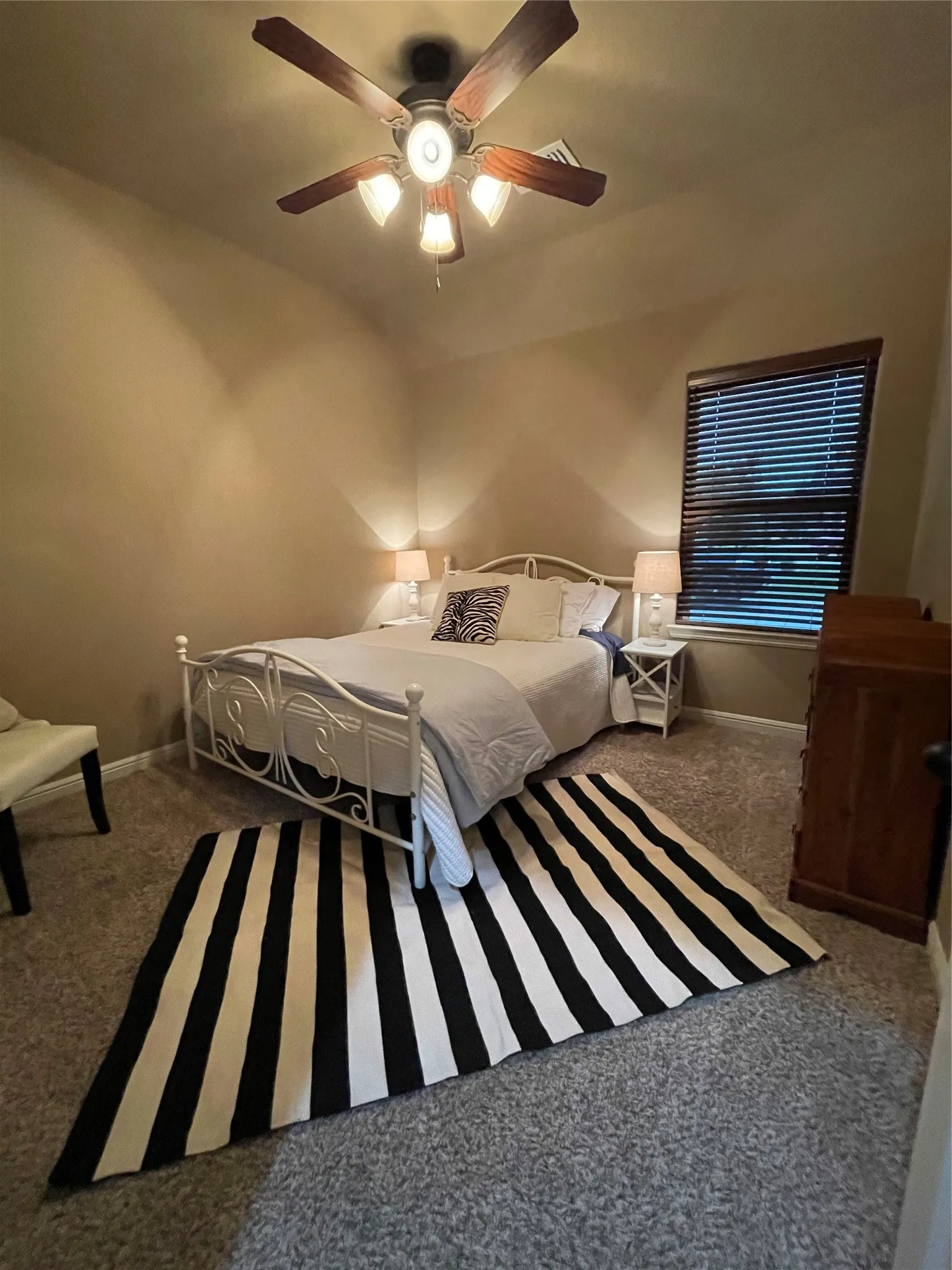 Vaulted ceilings, wood-finish ceiling fan with integrated lighting, window with wood-finish blinds, and wall-to-wall carpeting
