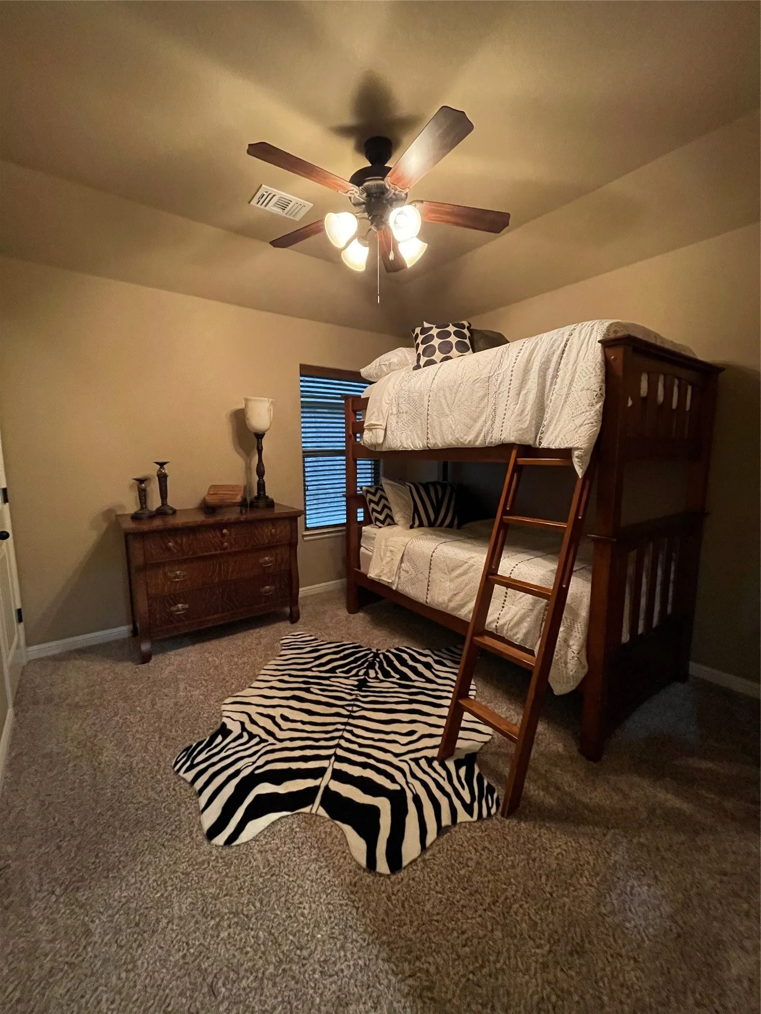 Carpeted flooring, window with horizontal blinds, and a ceiling fan with integrated lighting