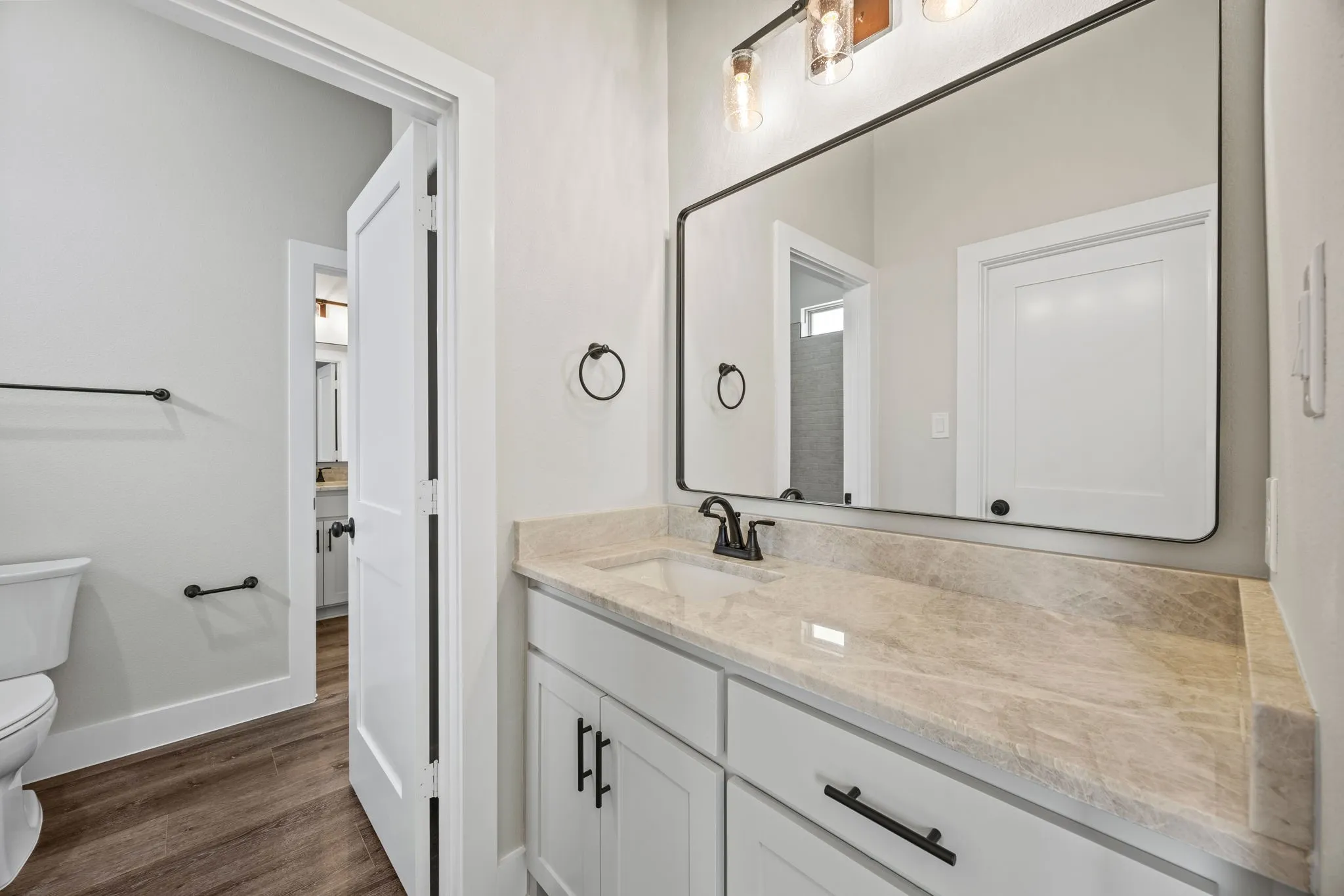 Vanity featuring a light-toned countertop, white cabinetry with black hardware, and a framed mirror