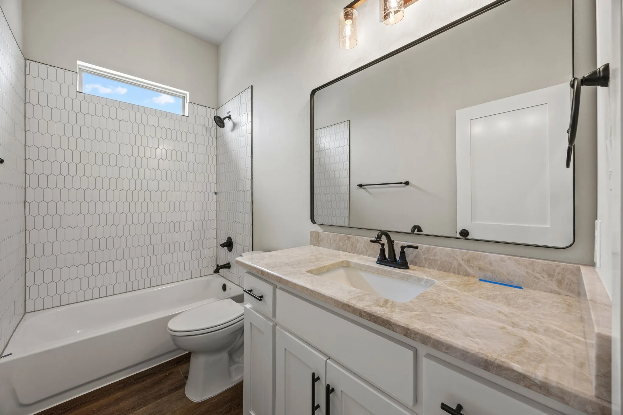 White vanity with black hardware, stone-finish countertop, and undermount sink